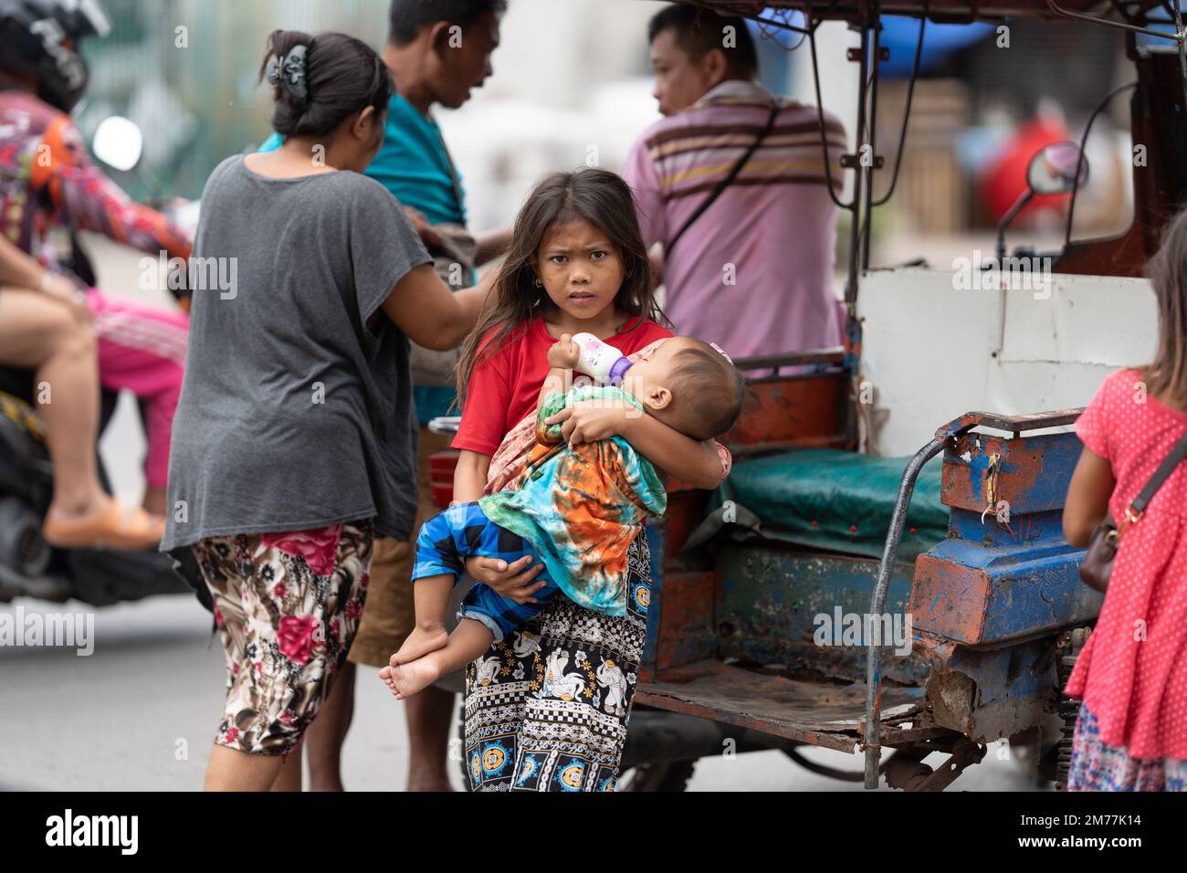 A young girl from the Badjao community holding a young baby in her arms.Philippines Stock Photo