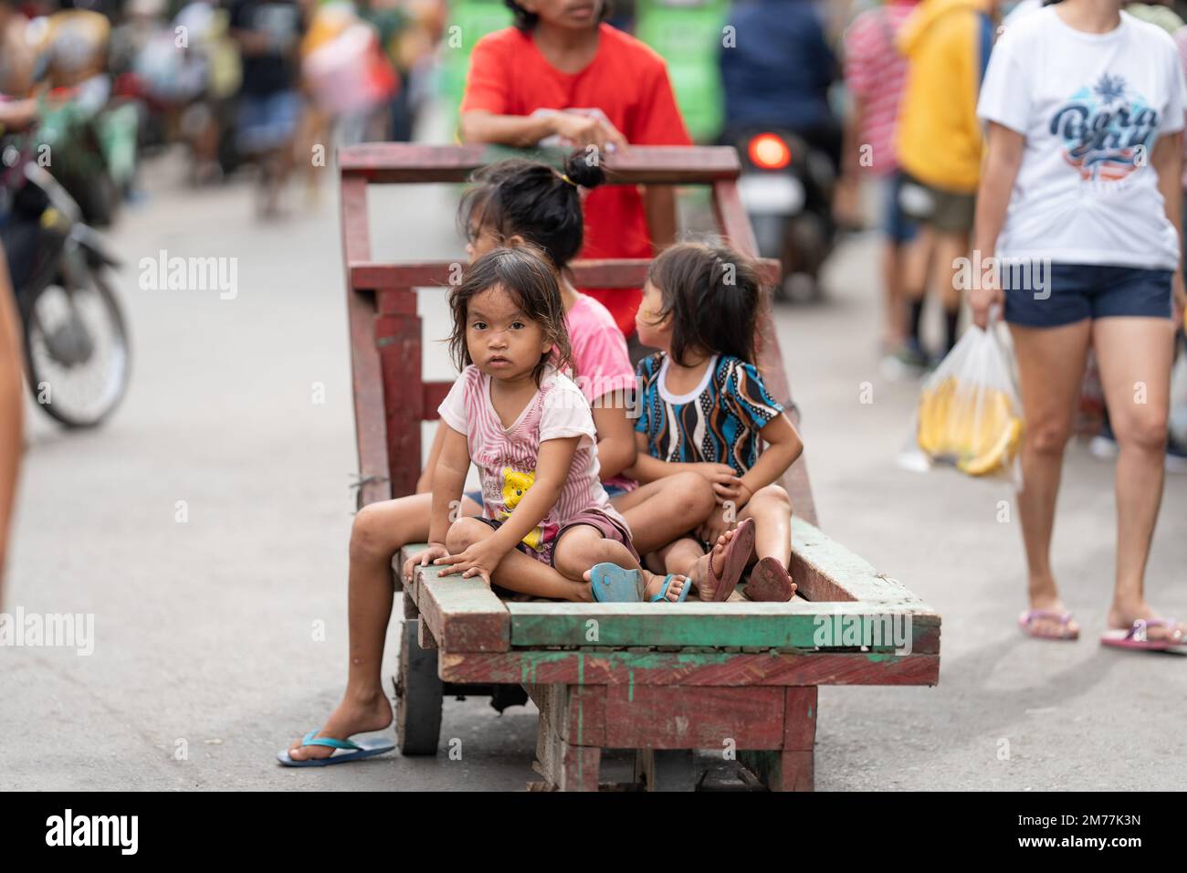 Young children in a poor community ride on a wooden pushcart, Philippines Stock Photo