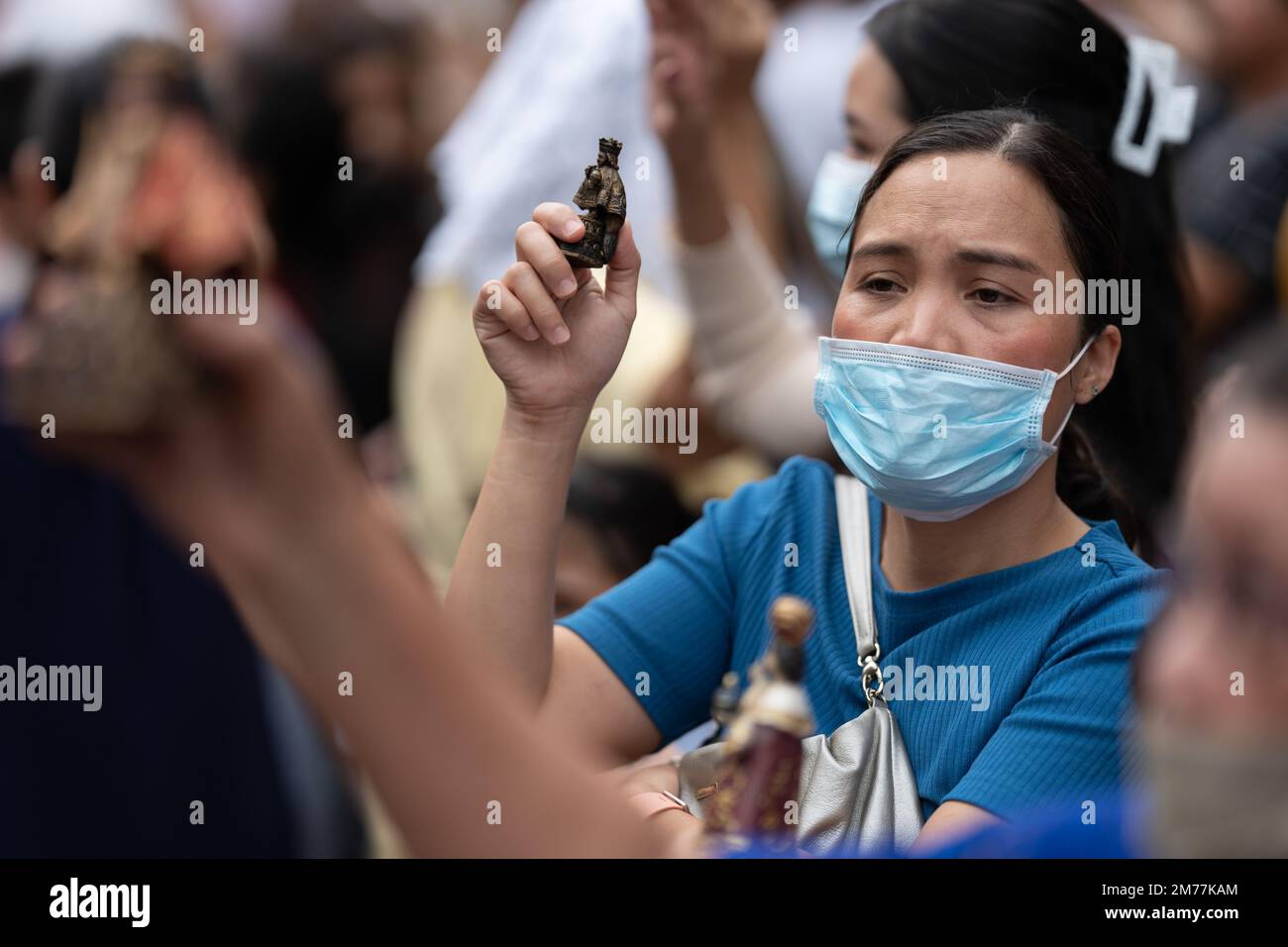 A woman wearing a face mask whilst holding a Santo Nino Figurine outside of the Basilica del Sant Nino church in Cebu City, Philippines Stock Photo