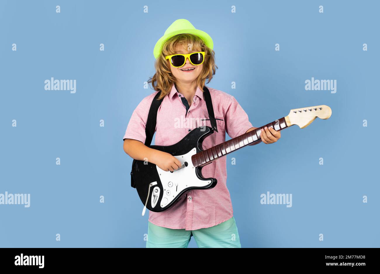 Child musician guitarist playing electric guitar. Cute boy plays on the electric guitar with funny glasses. Stock Photo