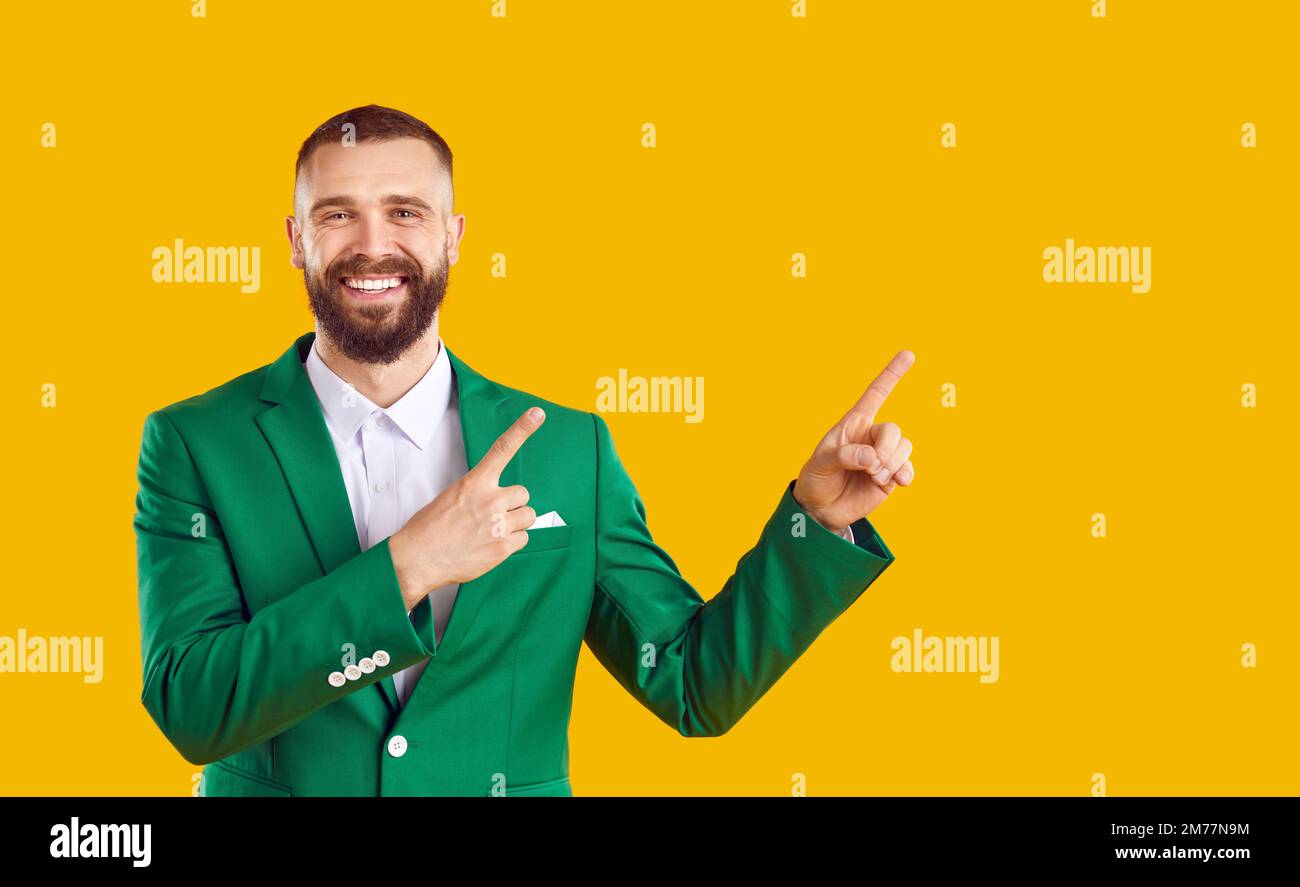 Happy man invites you to St Patrick's Day party and points at copy space on yellow background Stock Photo
