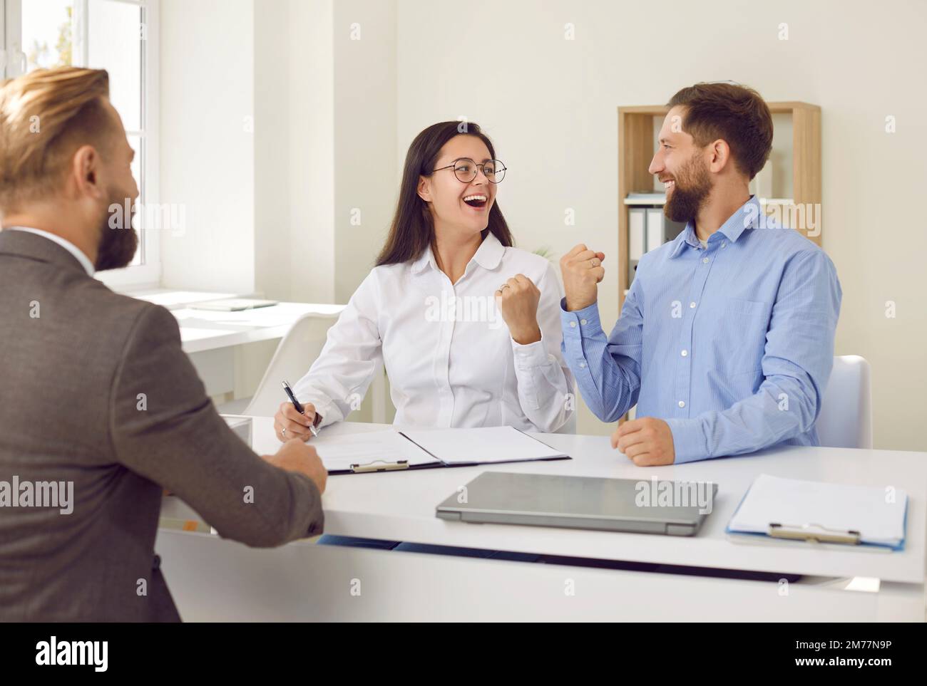 Joyful excited family rejoices during signing of contract of sale or approval of loan. Stock Photo