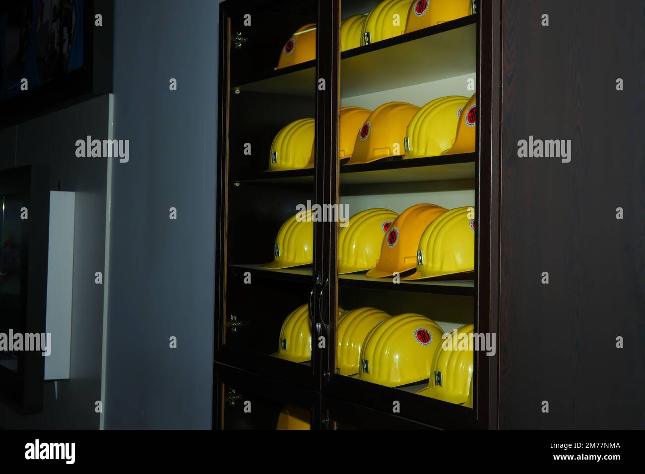 Yellow helmets of mine workers on the shelf with white wall at the background Stock Photo
