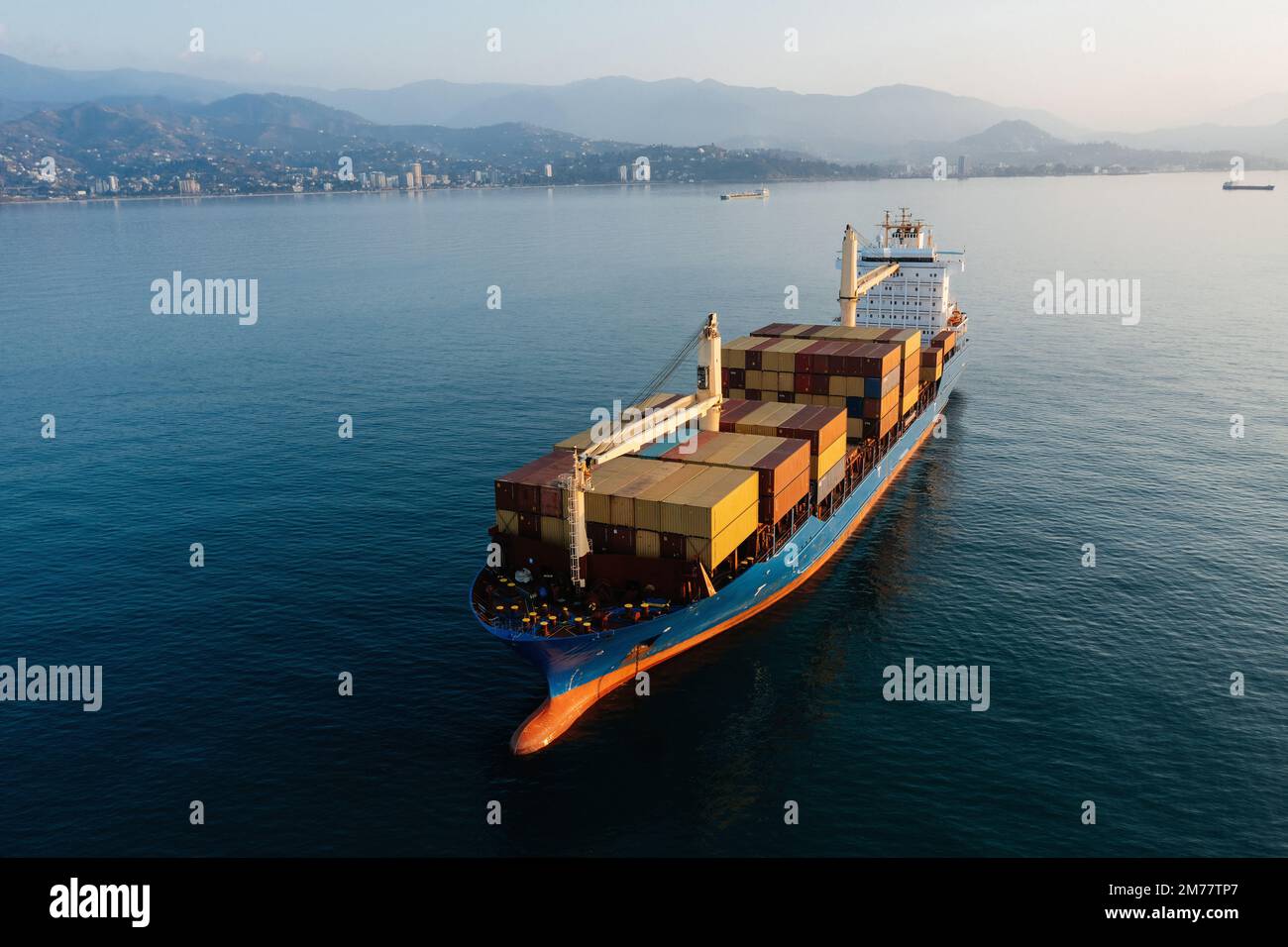 Cargo ship with containers in the open sea, aerial drone view. Stock Photo