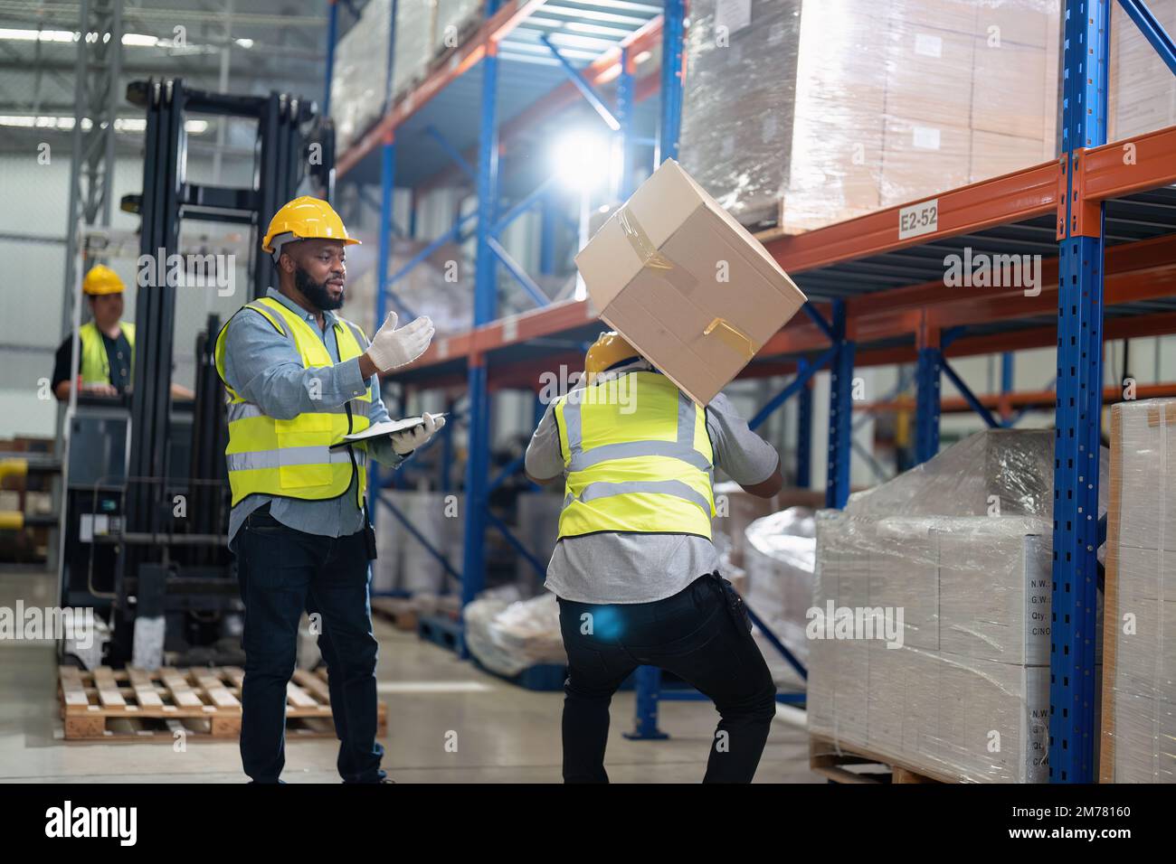 African american working in warehouse got accident from carry box, forklift truck working near by Stock Photo