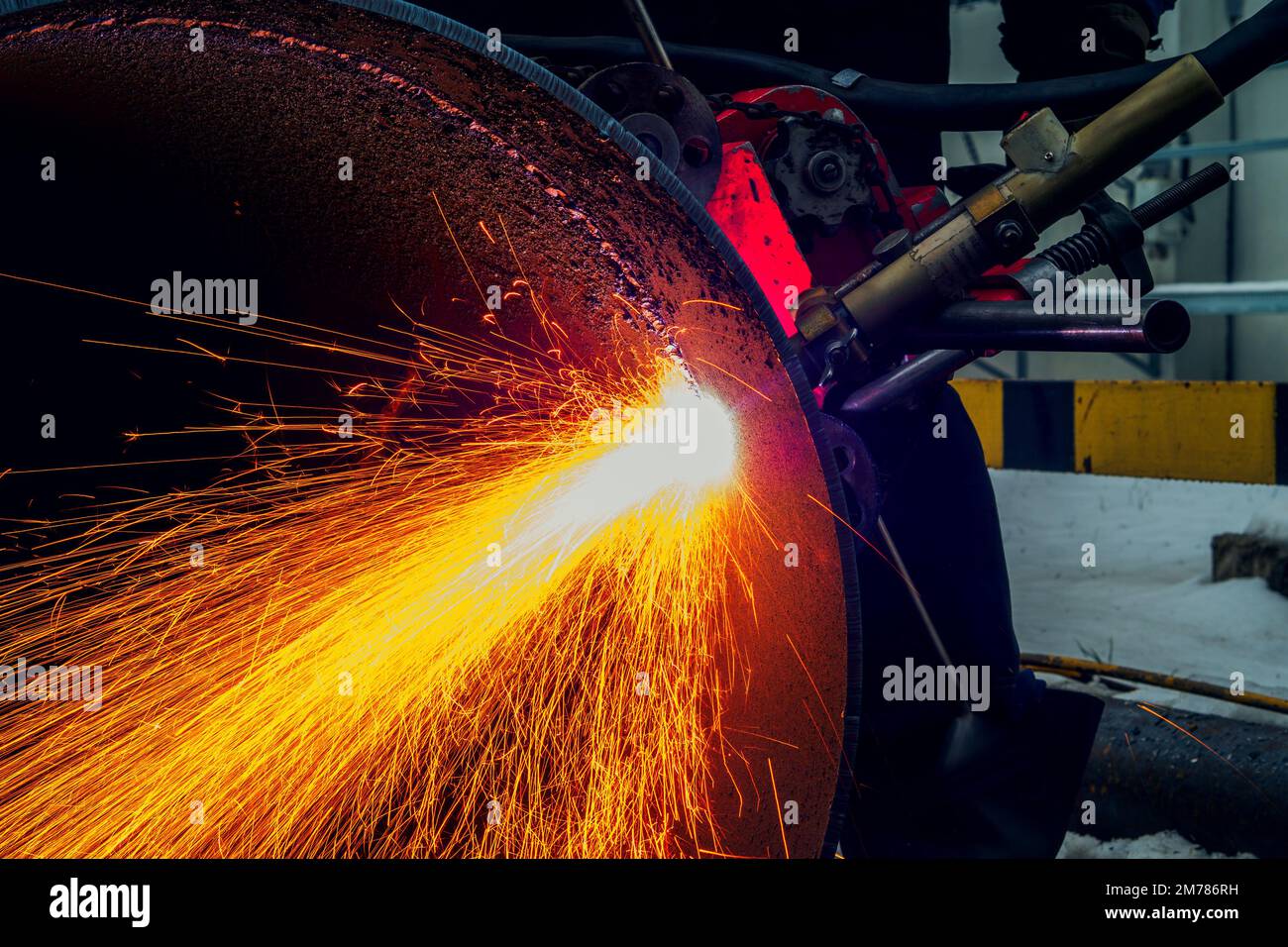 Working welder cuts metal and sparks fly. Gas cutting of large diameter pipes with acetylene and oxygen. Industrial metal cutting in oil and gas industry. Stock Photo