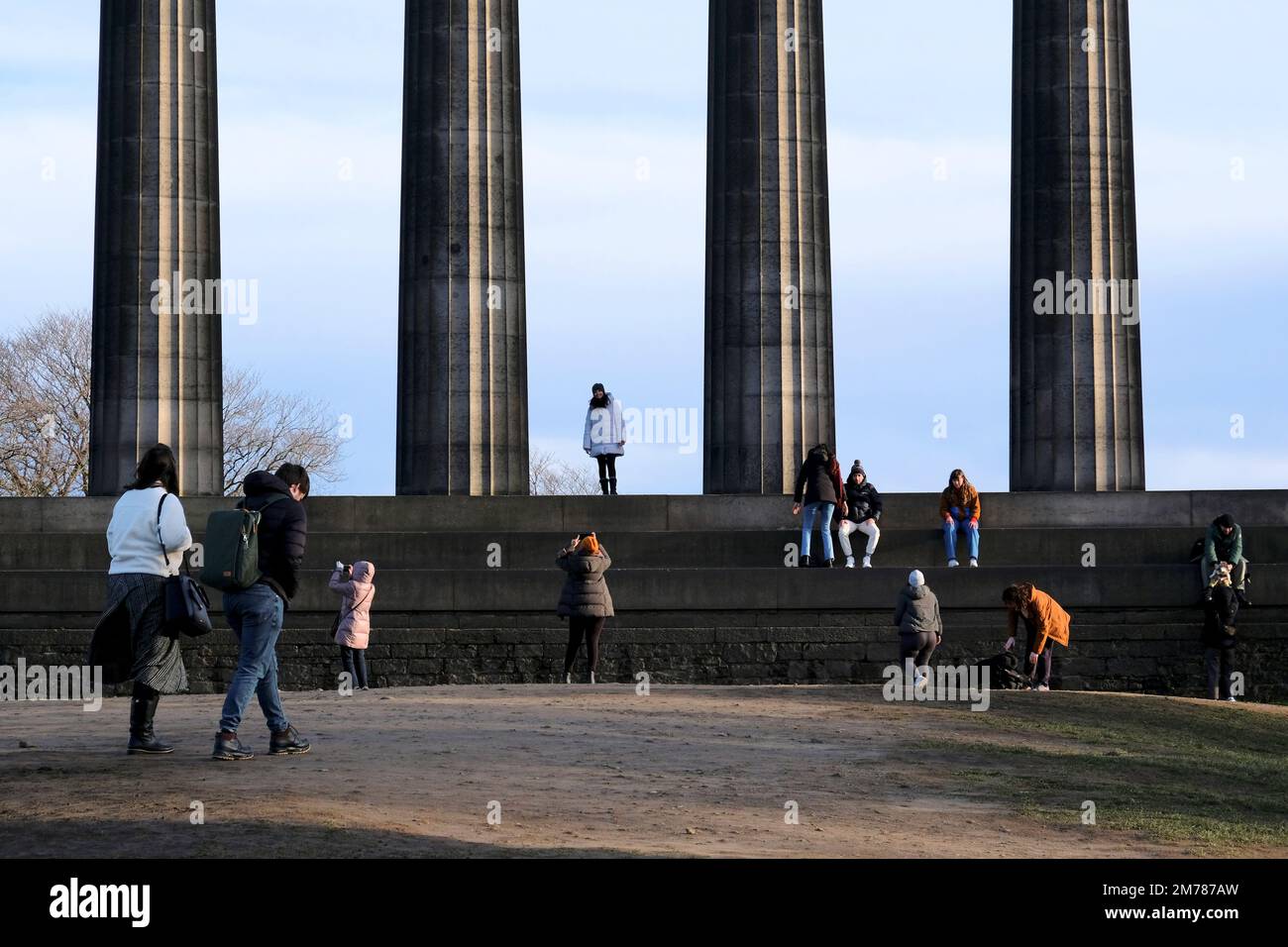 Edinburgh, Scotland, UK. 8th January 2023. Visitors on Calton hill wrapped up against the cold blustery wind and changeable weather conditions. People on the the National Monument. Credit: Craig Brown/Alamy Live News Stock Photo