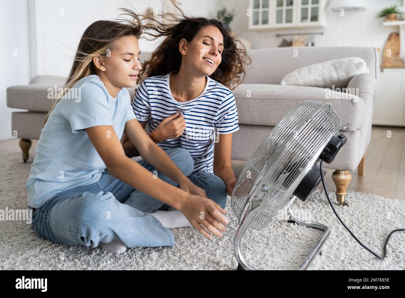 Mother and daughter cooling down while sitting on floor in front of