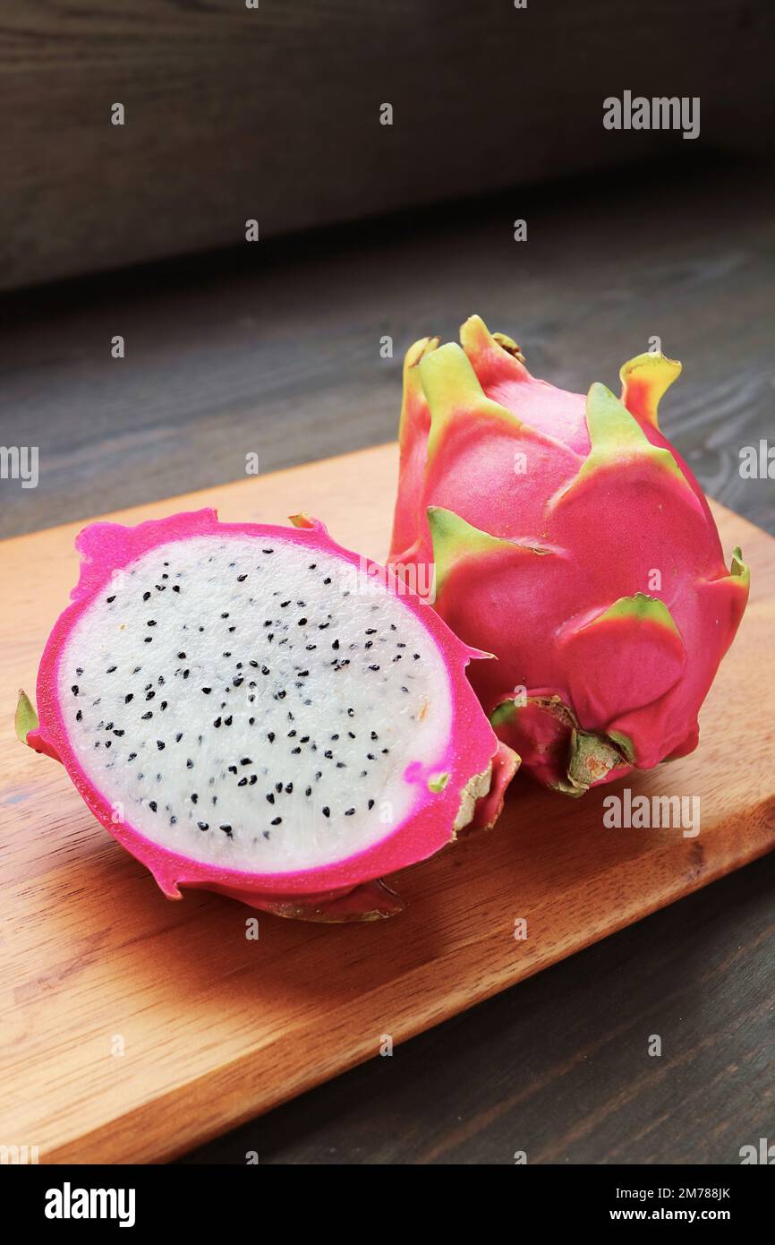 Fresh Ripe Dragon Fruit Cut in Half with a Whole Fruit on Wooden Chopping Board Stock Photo
