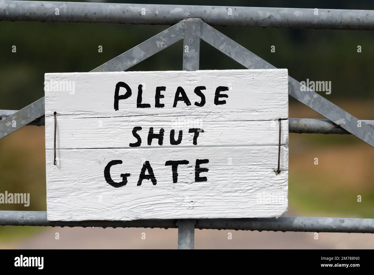 Narrow country lane with a gate on, sign on the gate saying 'Shut the gate' on it. Highlands of Scotland, UK. Stock Photo