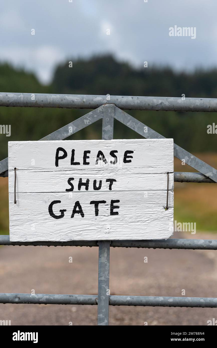Narrow country lane with a gate on, sign on the gate saying 'Shut the gate' on it. Highlands of Scotland, UK. Stock Photo