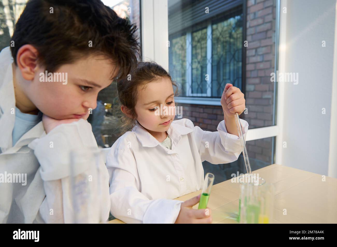 Adorable Caucasian schoolboy and schoolgirl in lab coats doing chemical ...