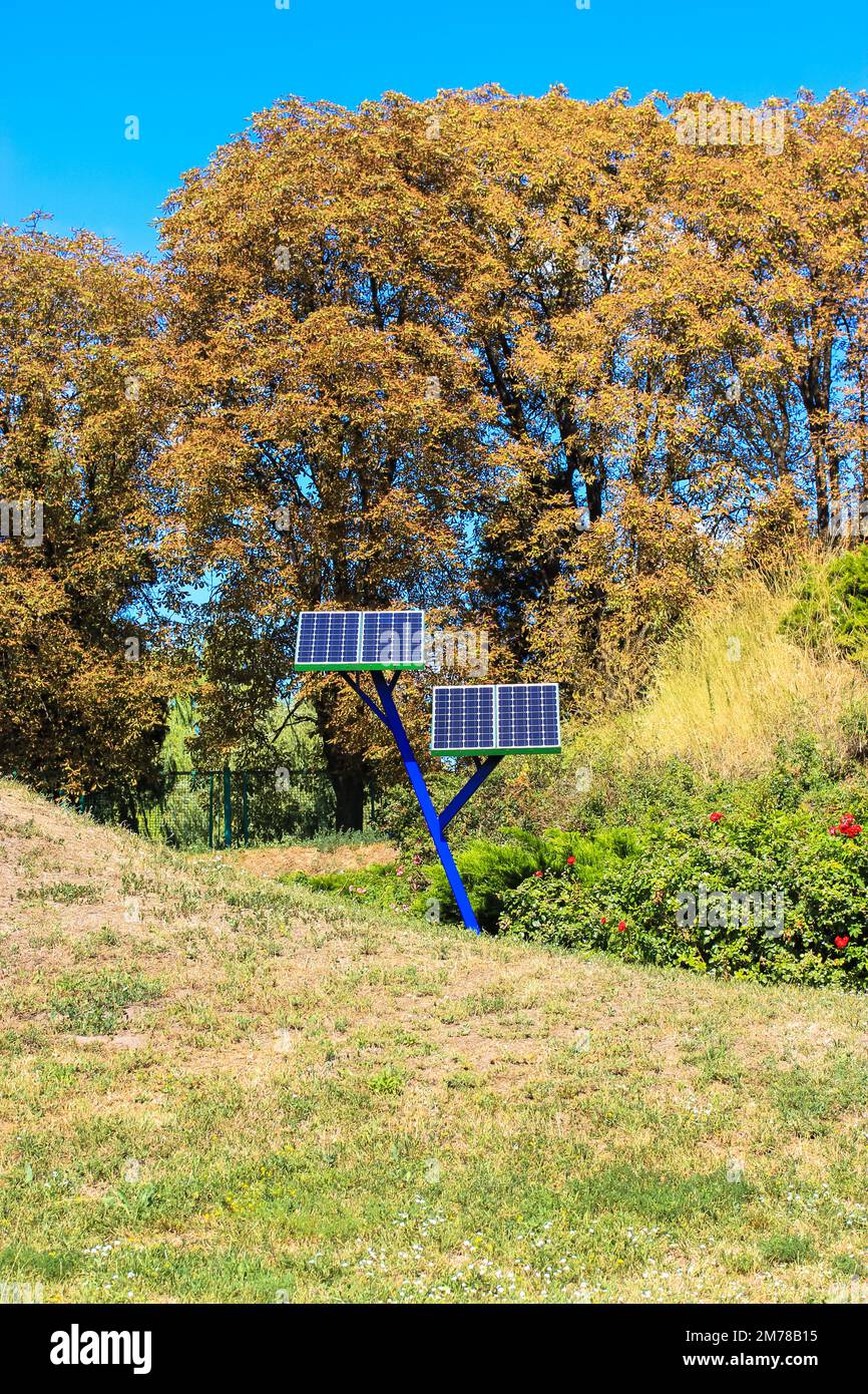 Small solar power array panels installed in a city park for charging cell phones. Using solar battery, generator in a gardening, agriculture, horticul Stock Photo