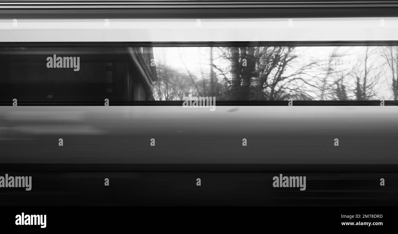 Abstract Reflection Of Trees And Railway Station In The Windows Of A Train Travelling At Speed, UK Stock Photo