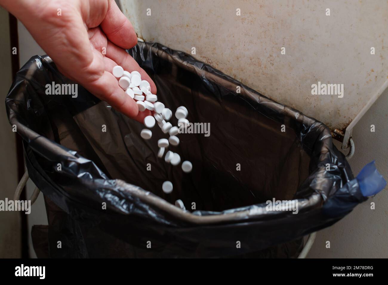 Hand throwing pills down a toilet Stock Photo - Alamy