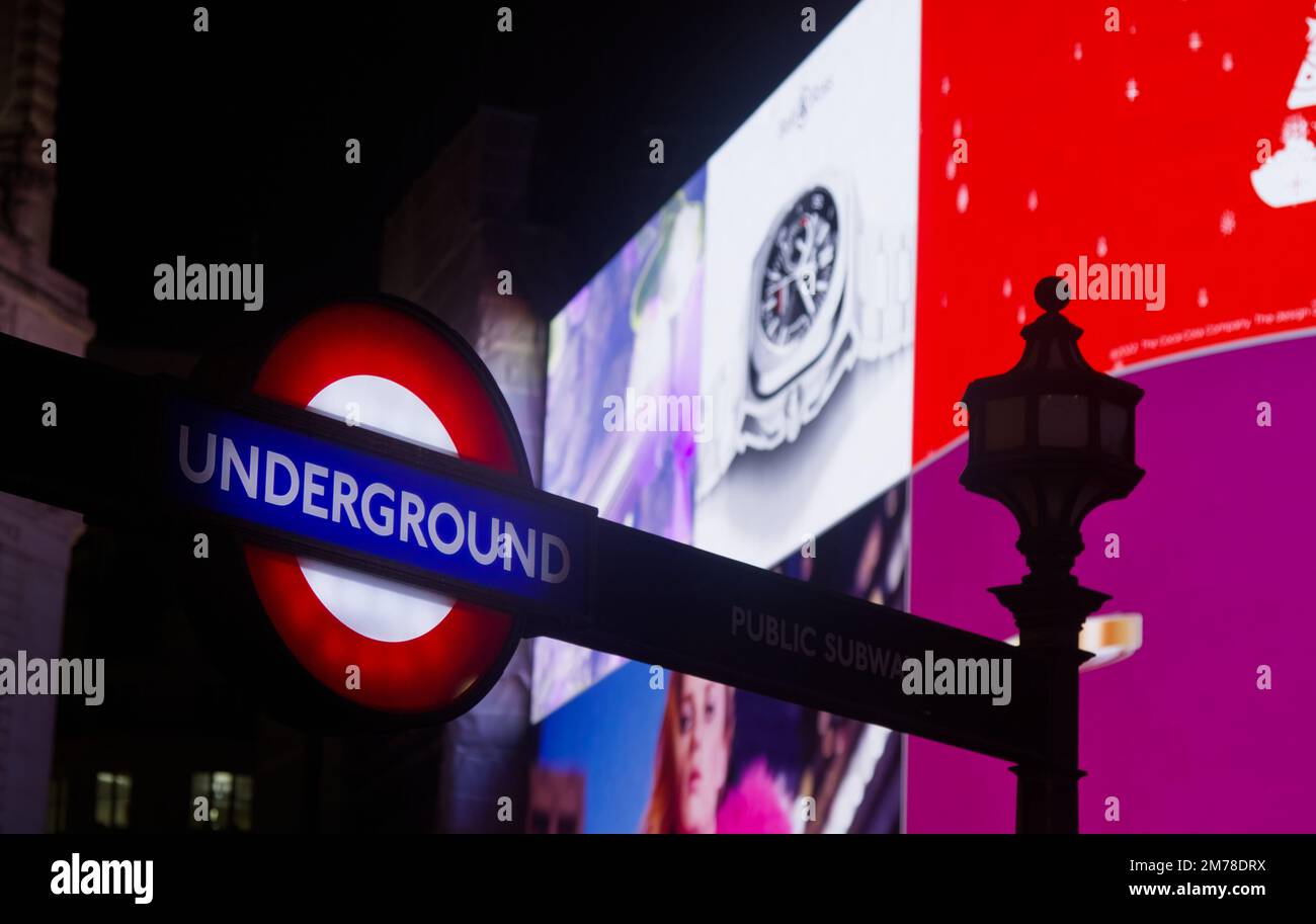 Illuminated Sign For The London Underground, Tube Or Subway In Front Of The Advertising Screens