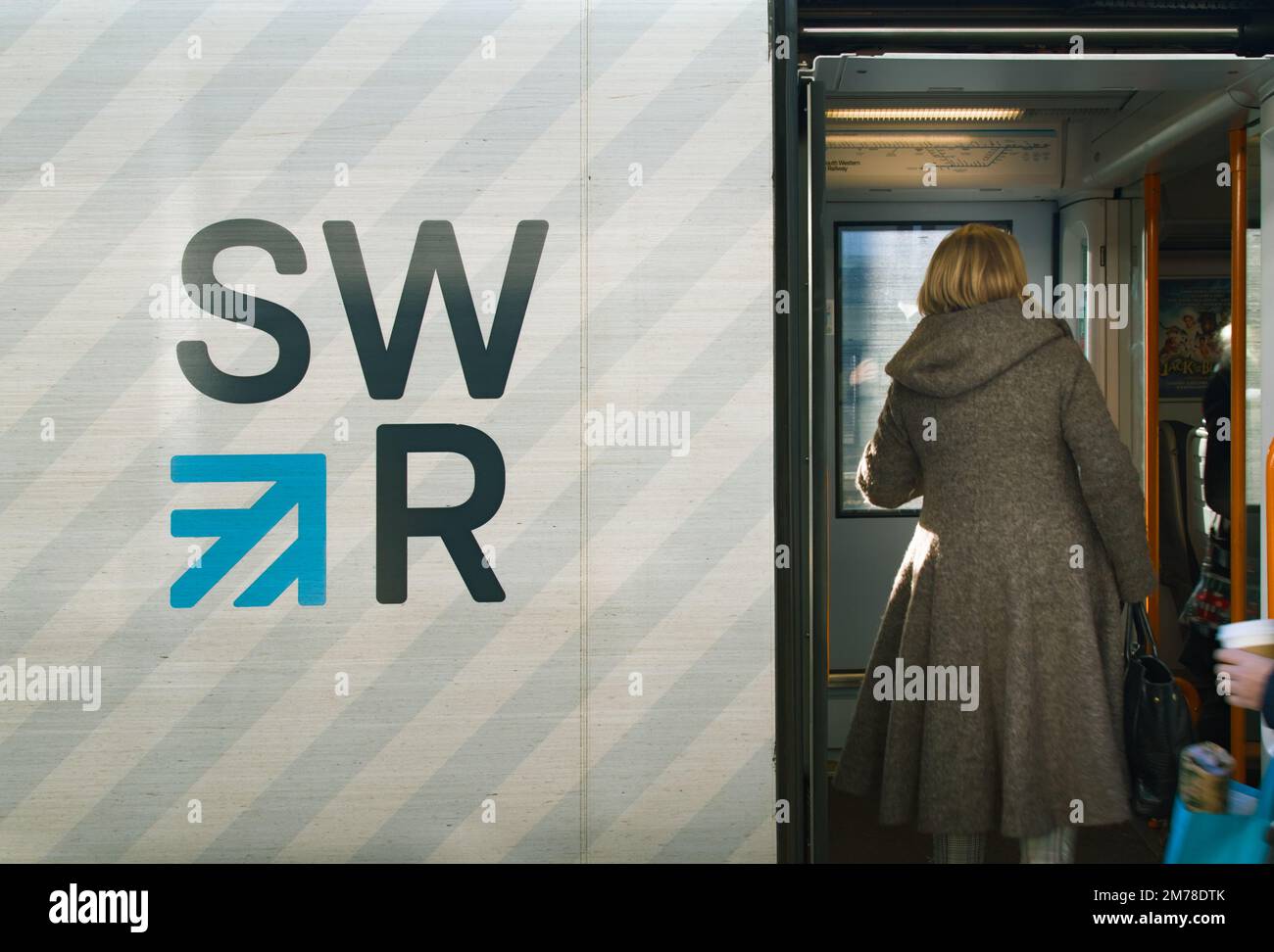 Woman Boarding A Train Carriage Of A South Western Rail Service Train With Logo, UK Stock Photo
