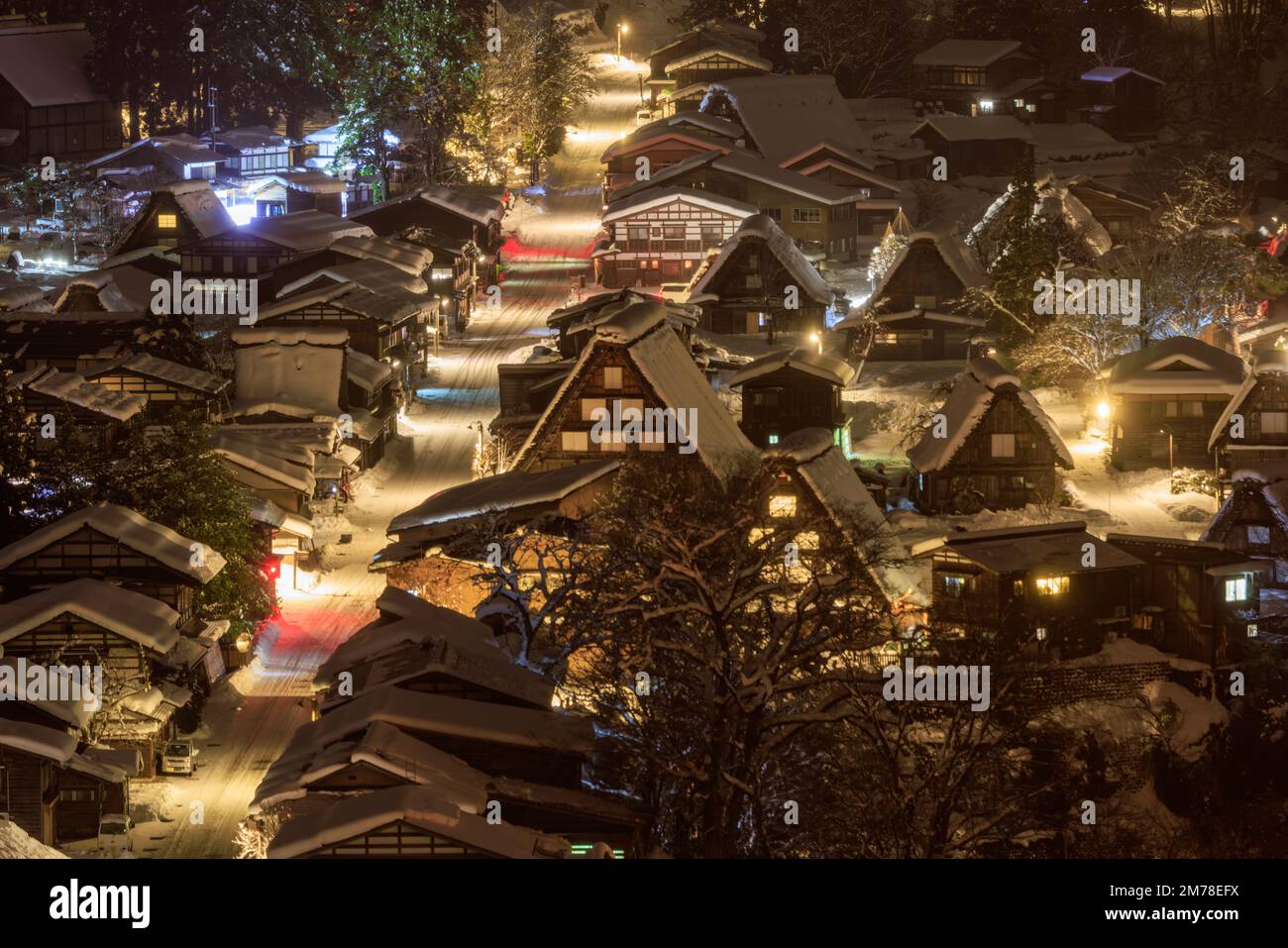 Well-lit main street down traditional Japanese village with winter snow Stock Photo
