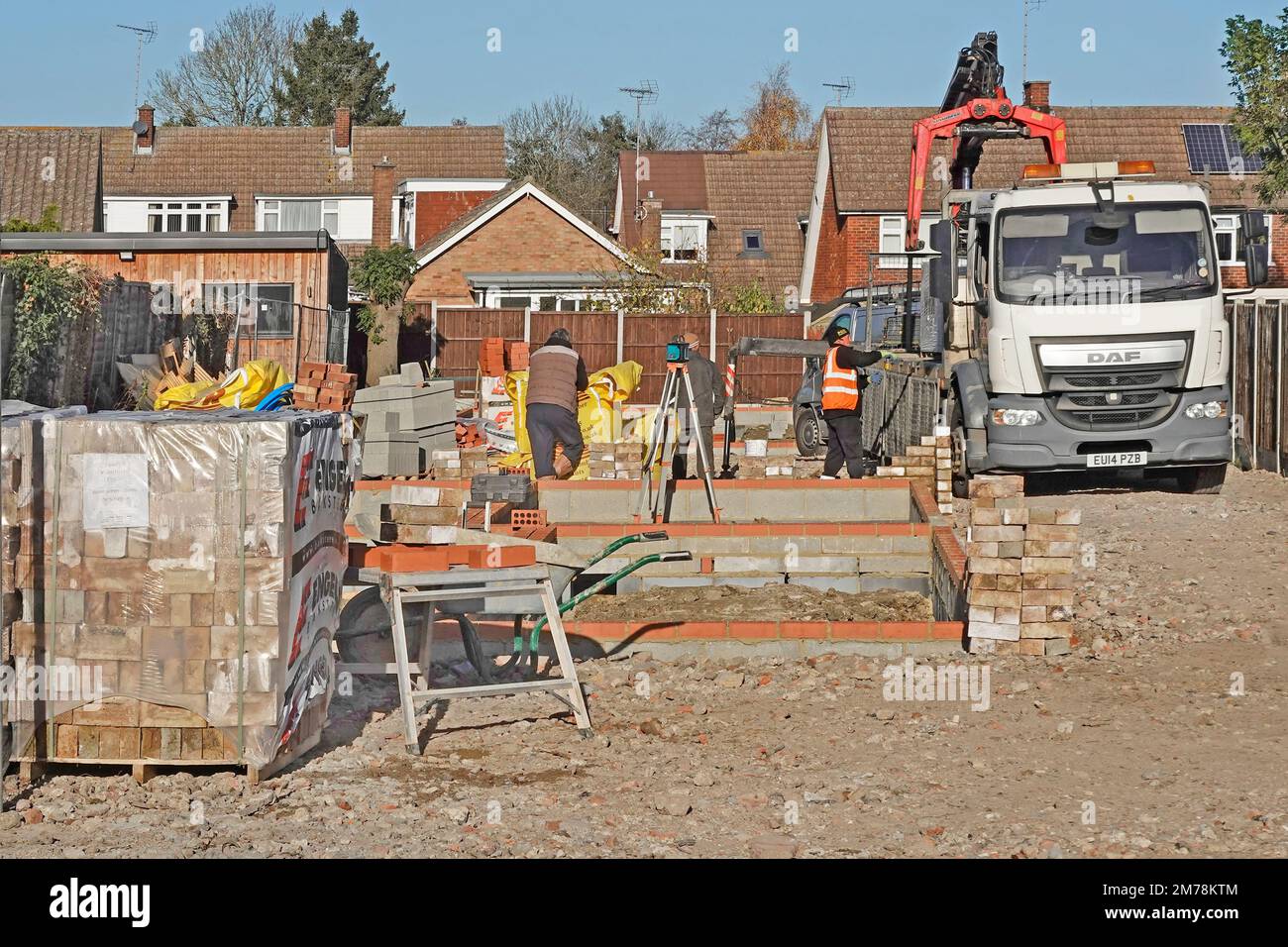 Lorry driver at controls crane offload hgv truck delivering building construction materials work in progress on detached house infill plot England UK Stock Photo