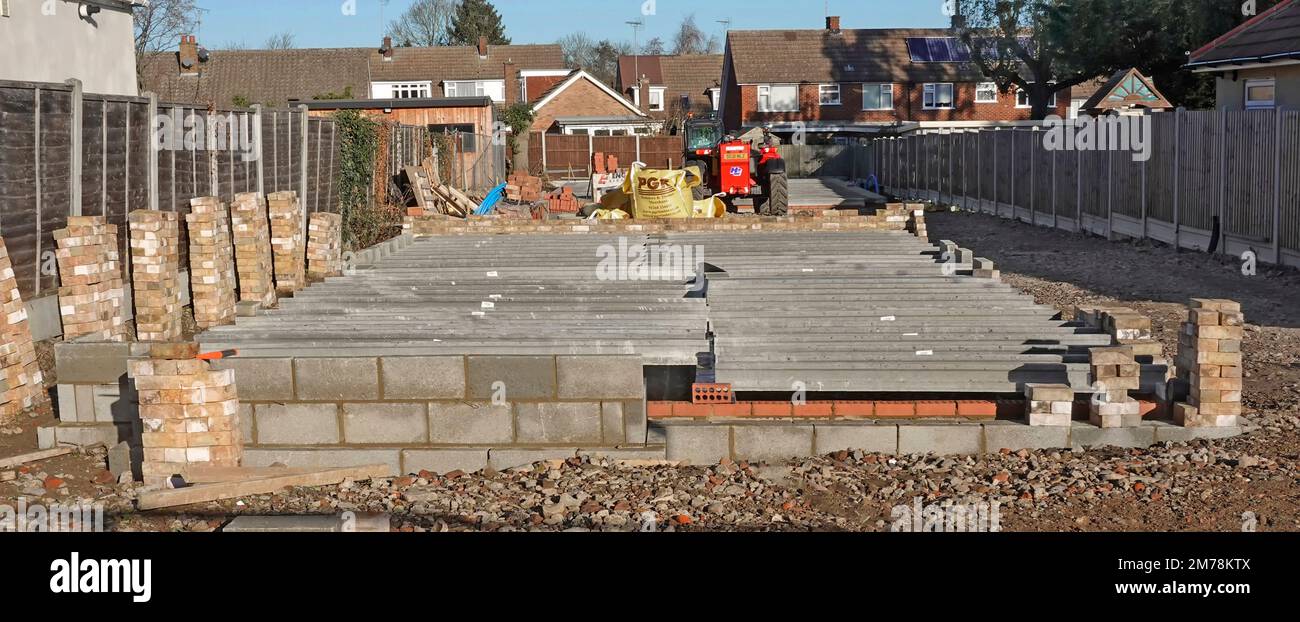 Detached home substructure construction progress precast concrete ground floor beam planks fork lifted from lorry onto load bearing walls England UK Stock Photo