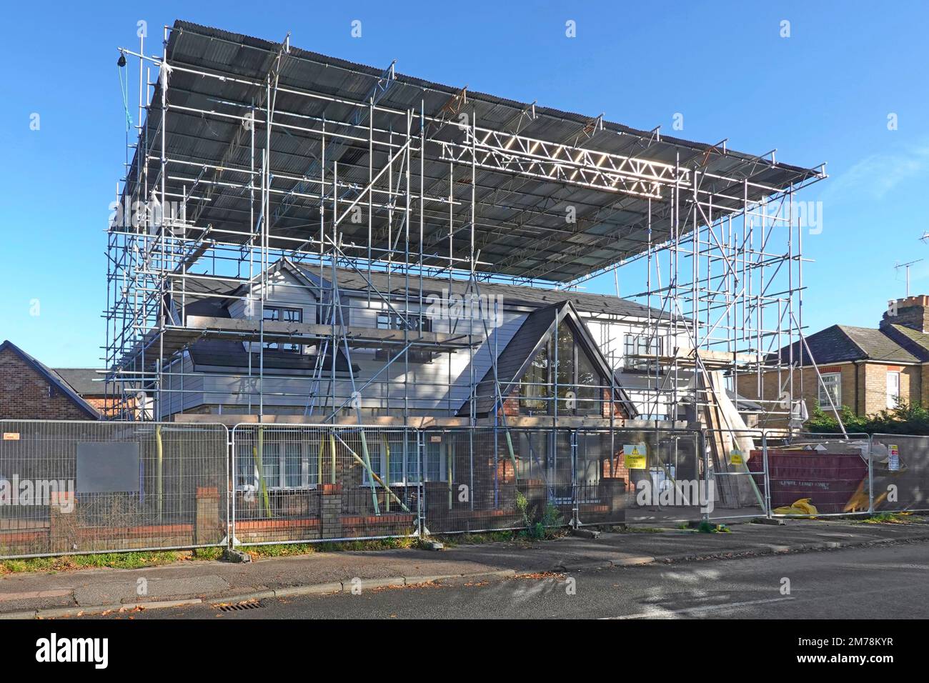 Building construction bungalow conversion to house vertical plastic sheeting removed corrugated roof on scaffolding ladder beam framework remains UK Stock Photo