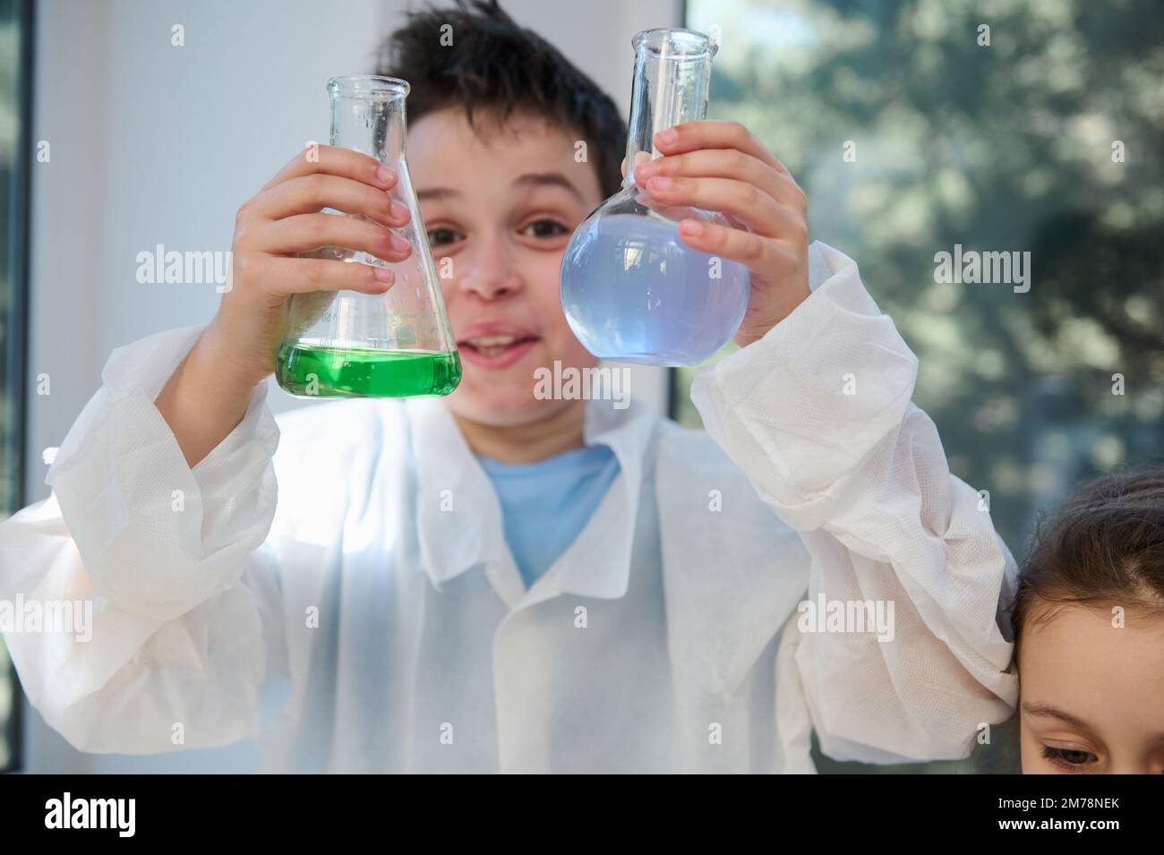 Details schoolboy's hands, hold lab flasks with chemical solutions