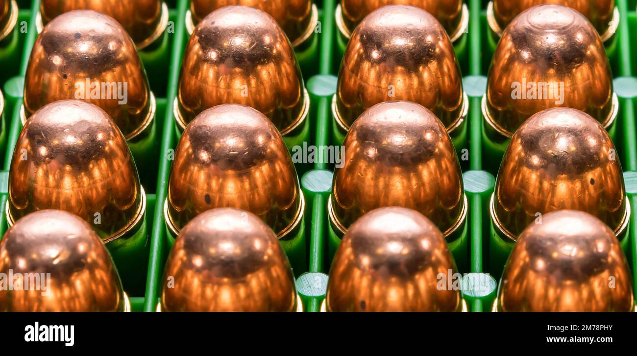 Twelve full metal jacket 45acp caliber bullets together in a green