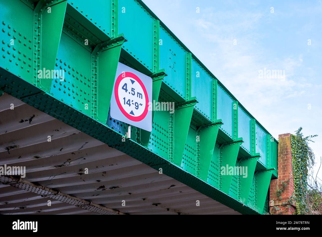 Green painted iron railway bridge with height limit restriction sign Stock Photo