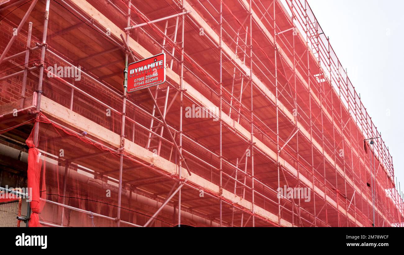 Scaffolding covered in red safety net Stock Photo