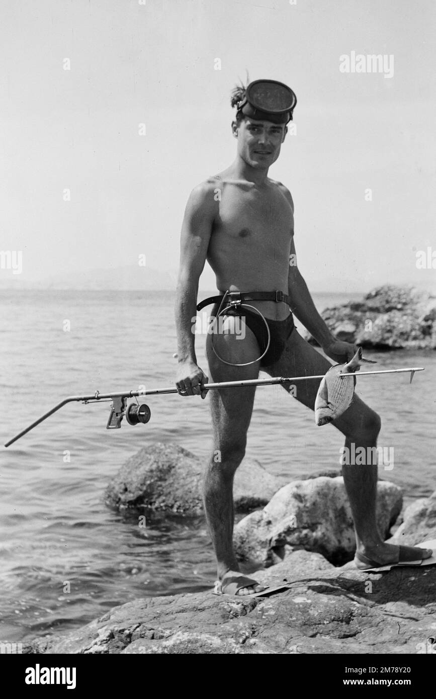 1940s Spear Fisherman Poses on Rocky Coast near Marseille France. Vintage black and white or monochrome photograph 1945. Stock Photo