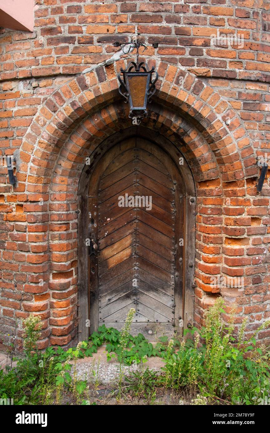 Entrance to a historic brick building with a hanging lantern above the door. Wall. Stock Photo