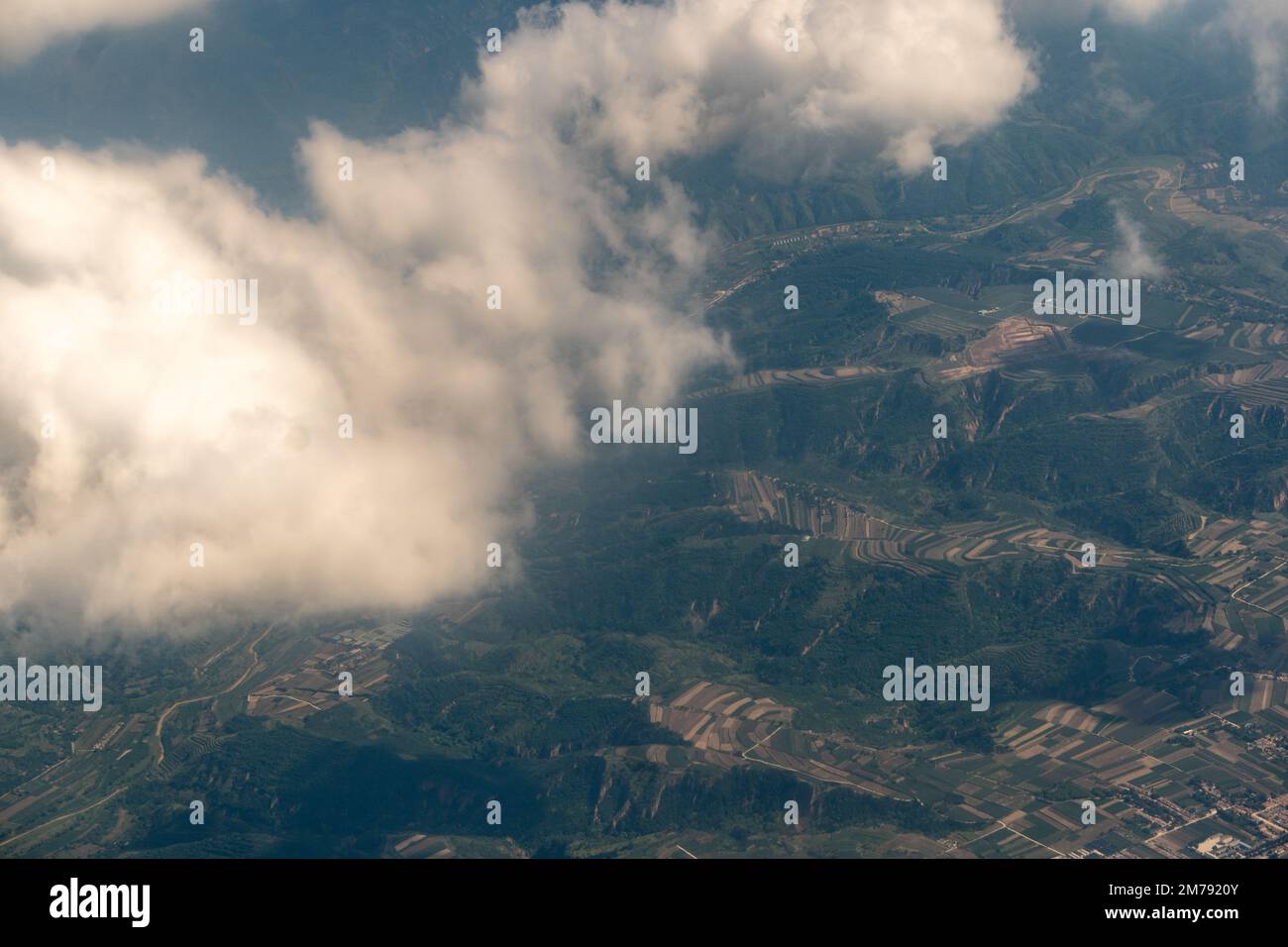 A beautiful shots of clouds over a green landscape on a sunny day Stock Photo