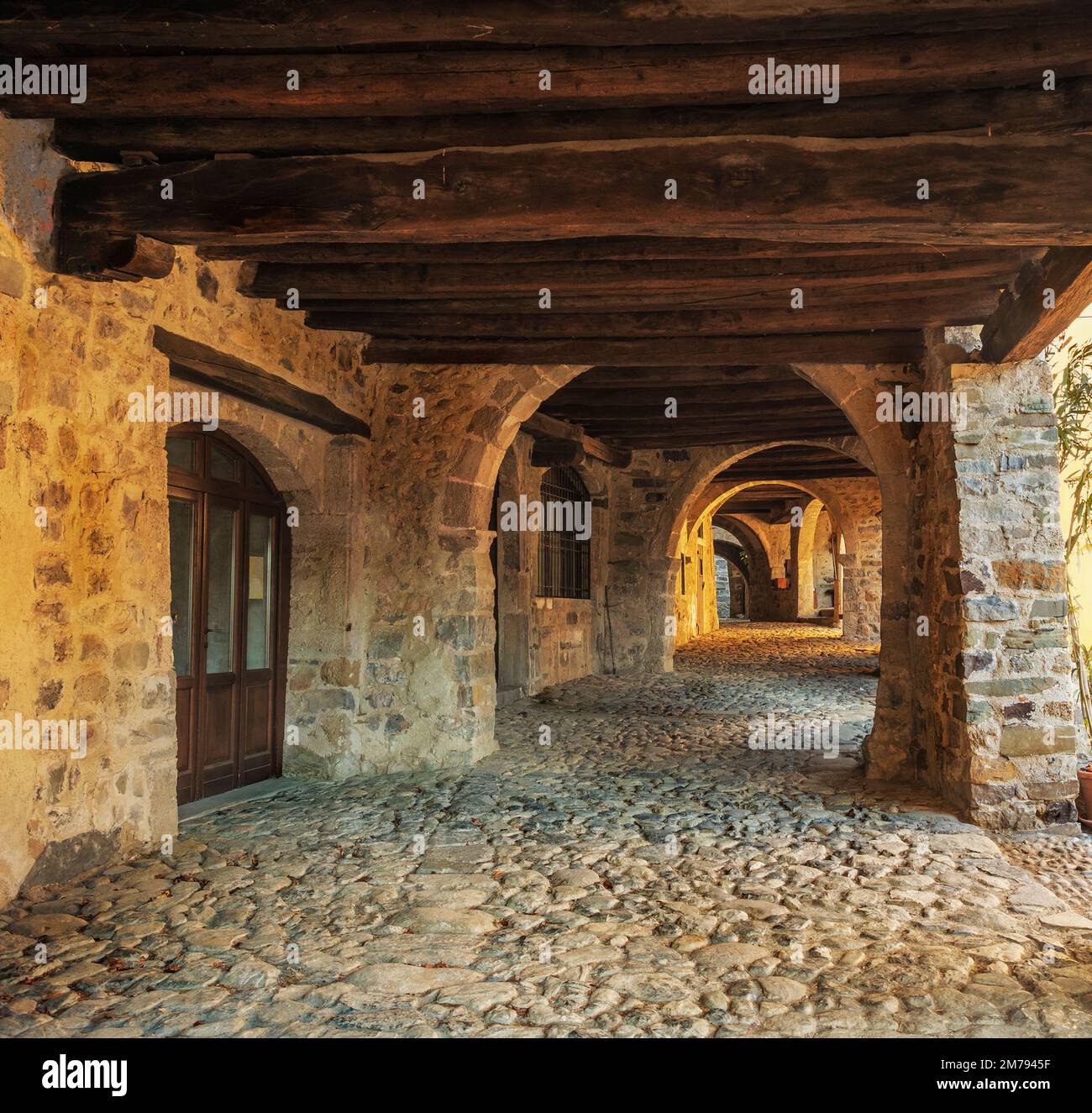 stone porch and wooden beam ceiling create a warm and intimate atmosphere in an ancient mountain village Stock Photo