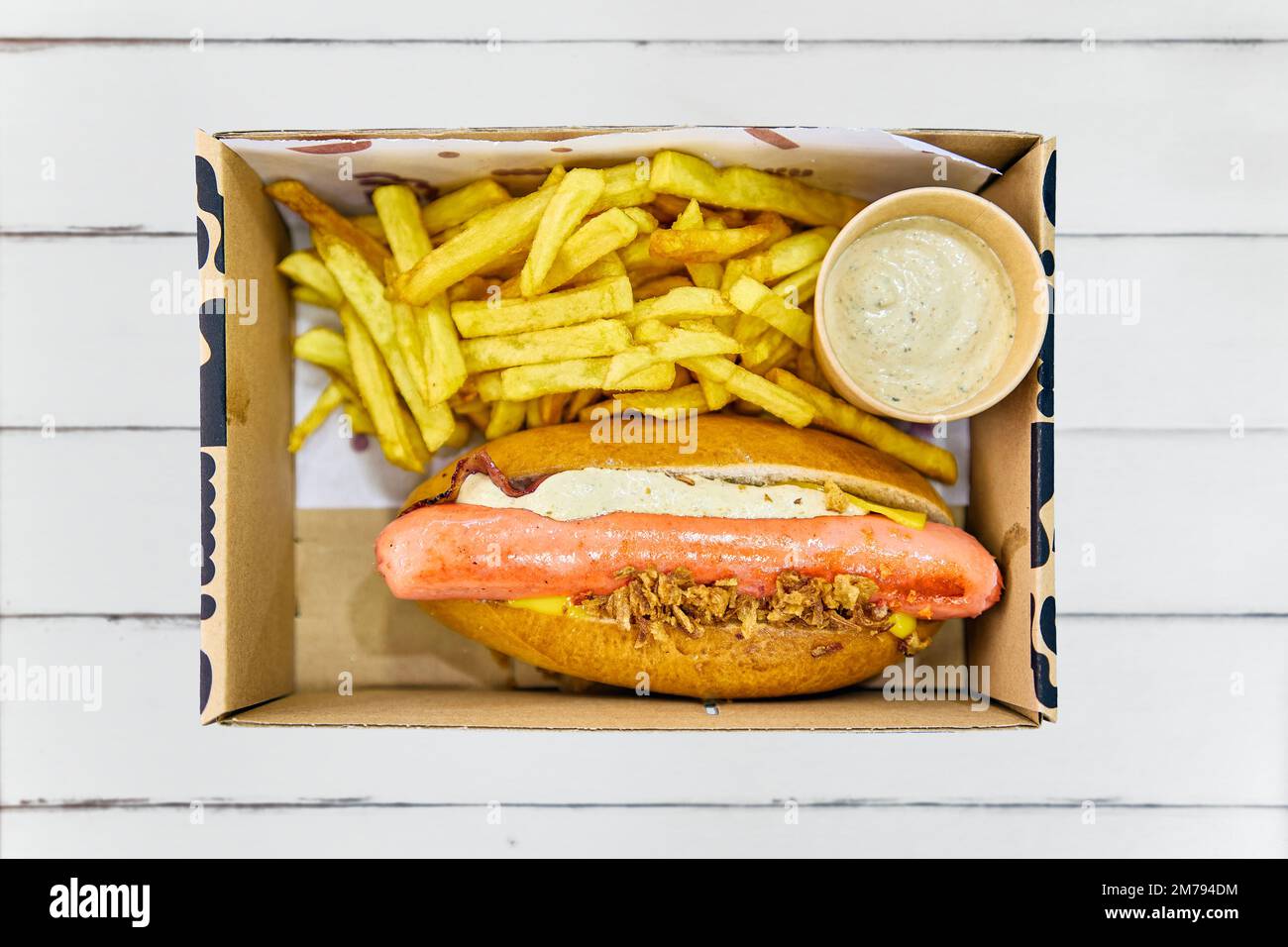 Hot dog menu, served in a cardboard box with fries and pickle mayonnaise. Stock Photo
