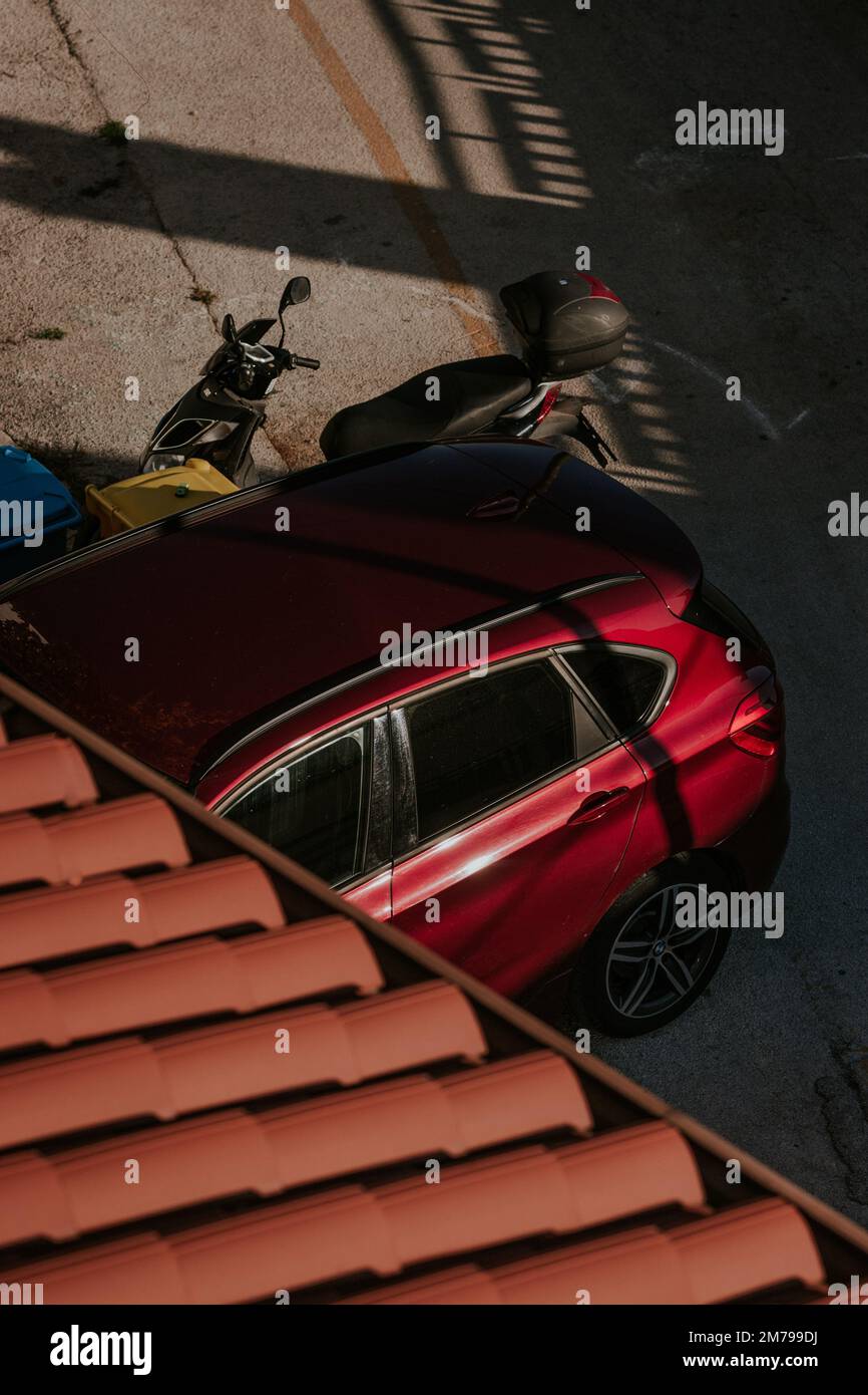 Beautiful red car and a scooter parked on a street in the summer Stock ...