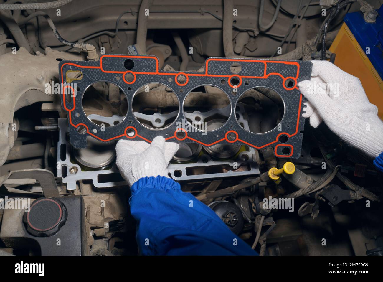 An auto mechanic installs a gasket on a car engine block. Service of