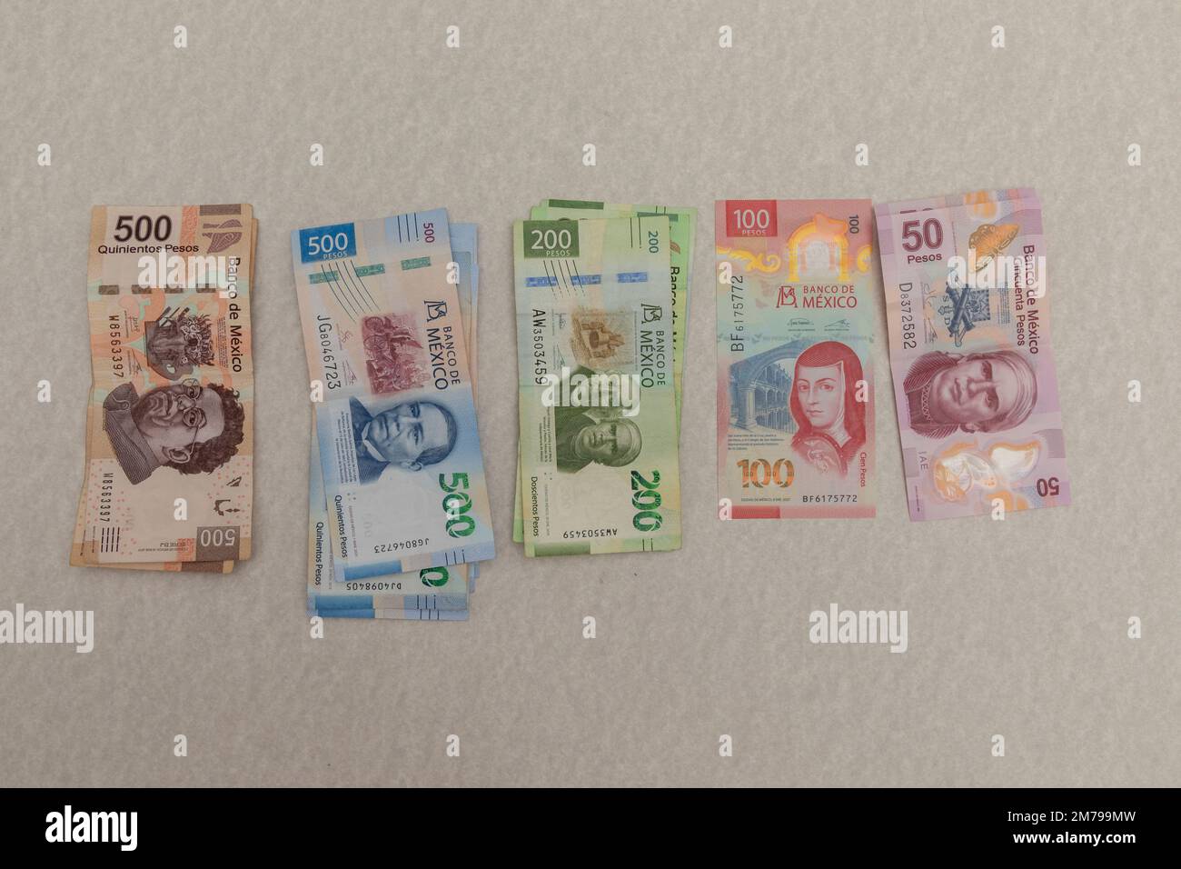 Mexican peso bills arranged by denomination on a marble surface. Stock Photo