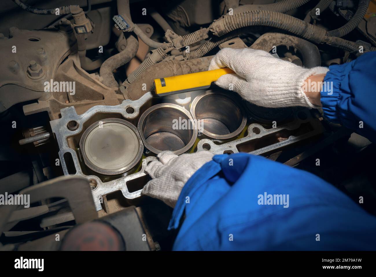 An auto mechanic inspects a car engine with a flashlight. Cylinder block with pistons without cover. Repair services. Maintenance, repair and diagnost Stock Photo