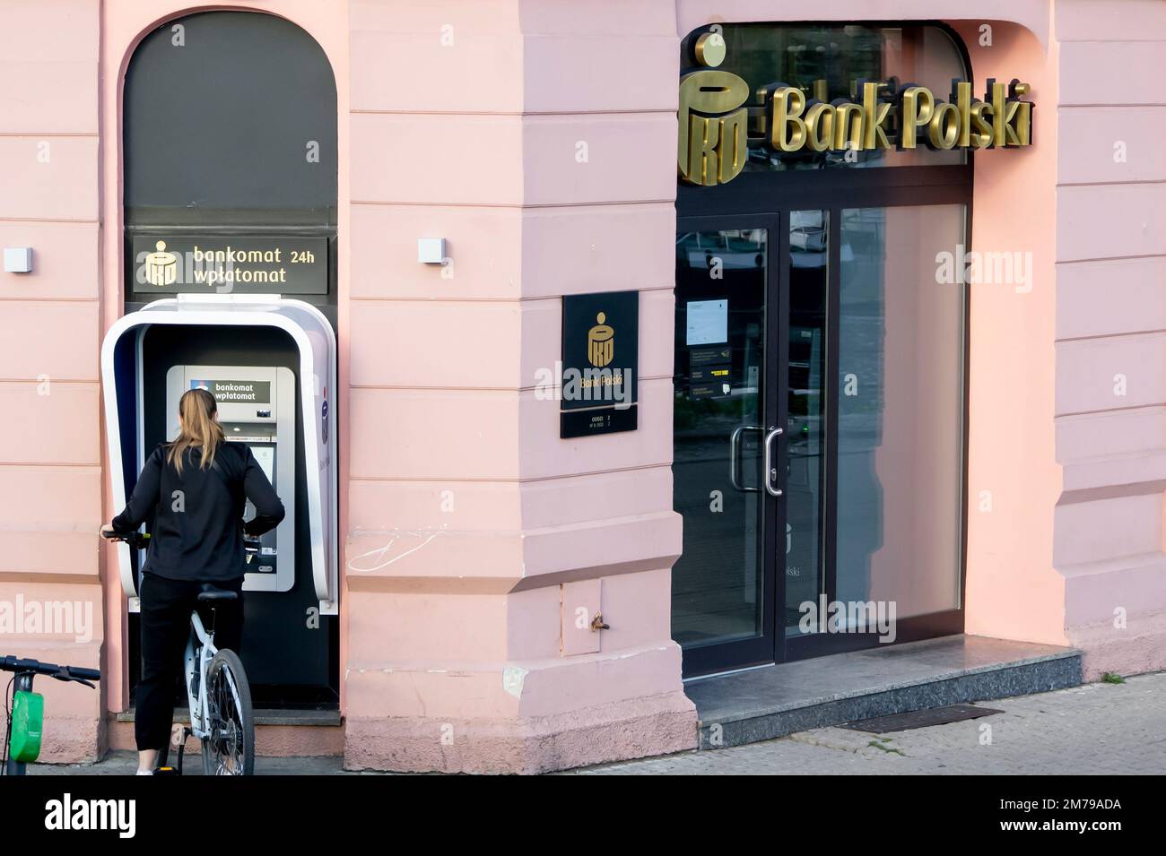 BYDGOSZCZ, POLAND - AUGUST 10, 2022: Bank Polski PKO office with a young woman withdrawing money from ATM Stock Photo