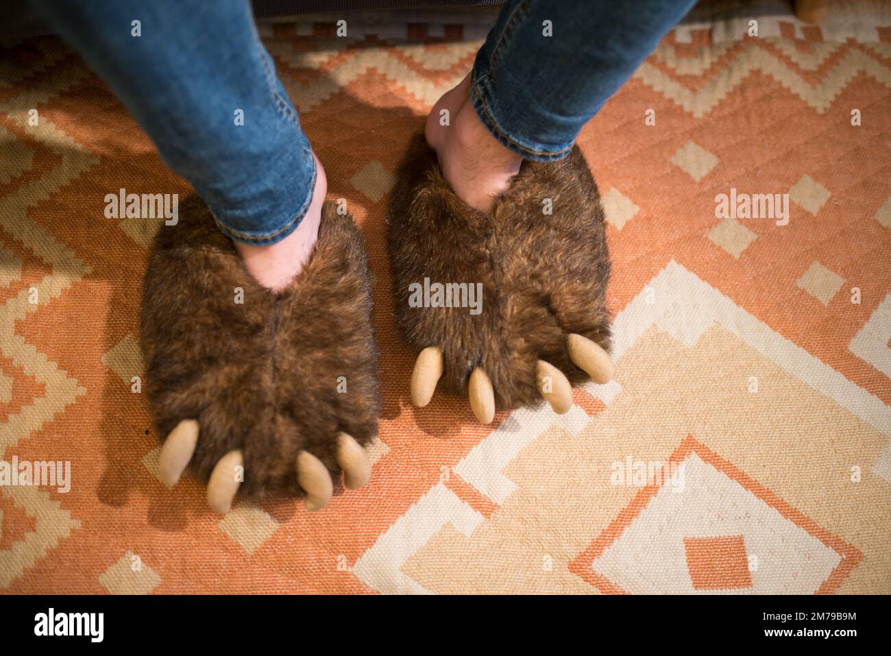 Feet with bear claws slippers. Seen from above. Interior Stock Photo