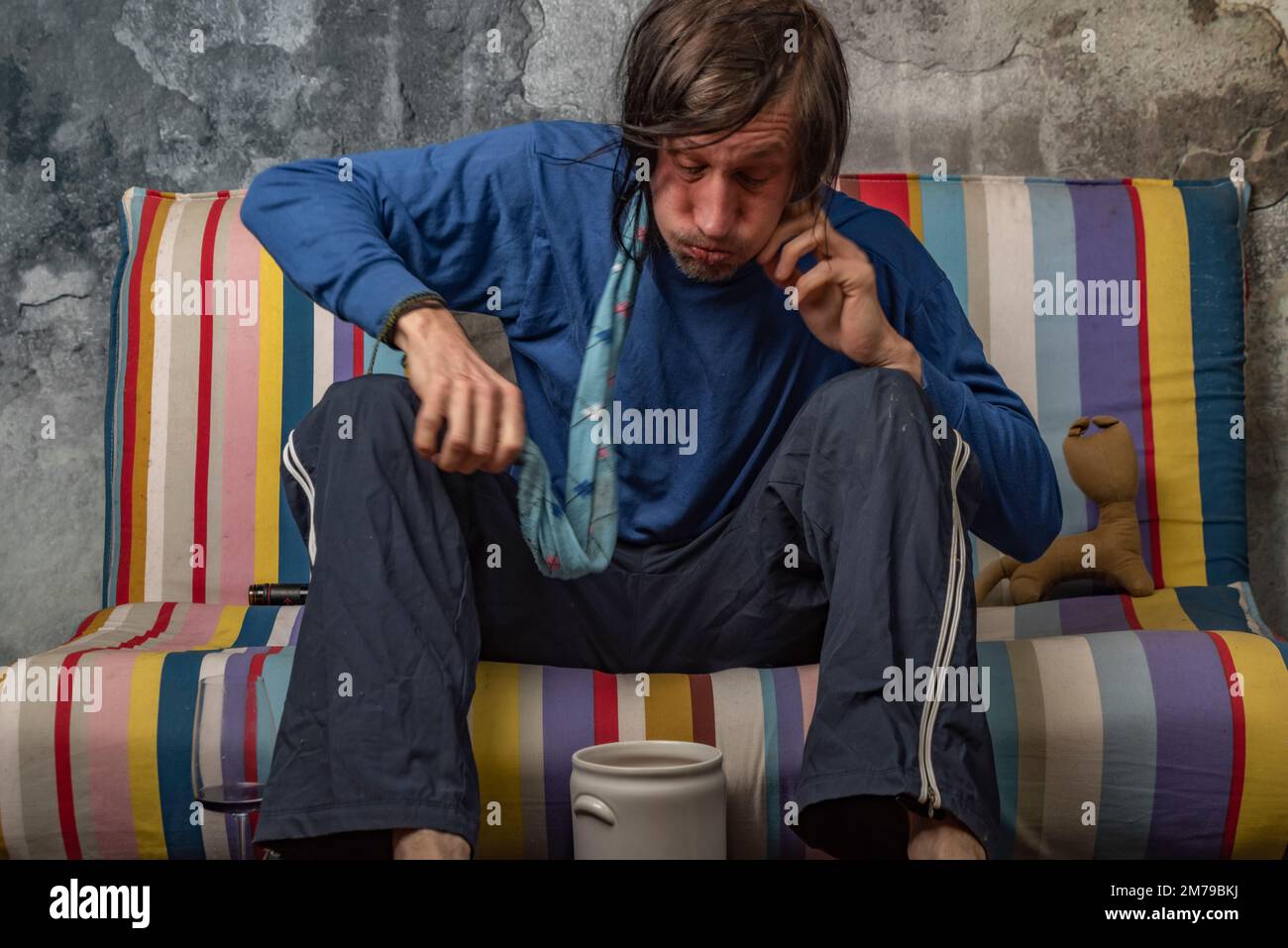 Man vomiting after drinking of alcohol on color sofa with old stone
