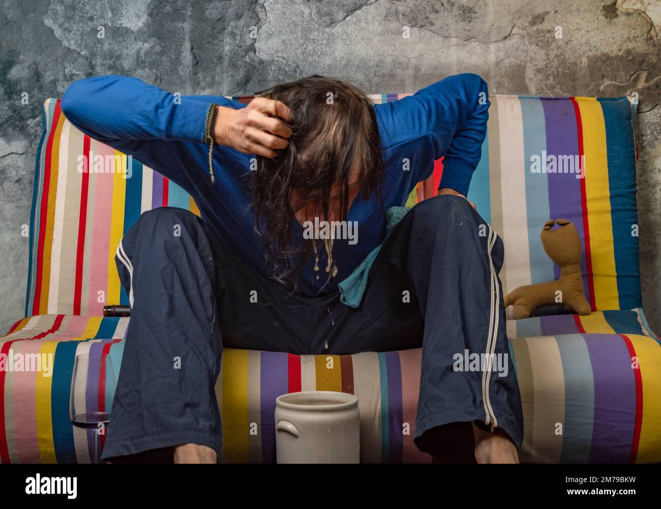 Man vomiting after drinking of alcohol on color sofa with old stone