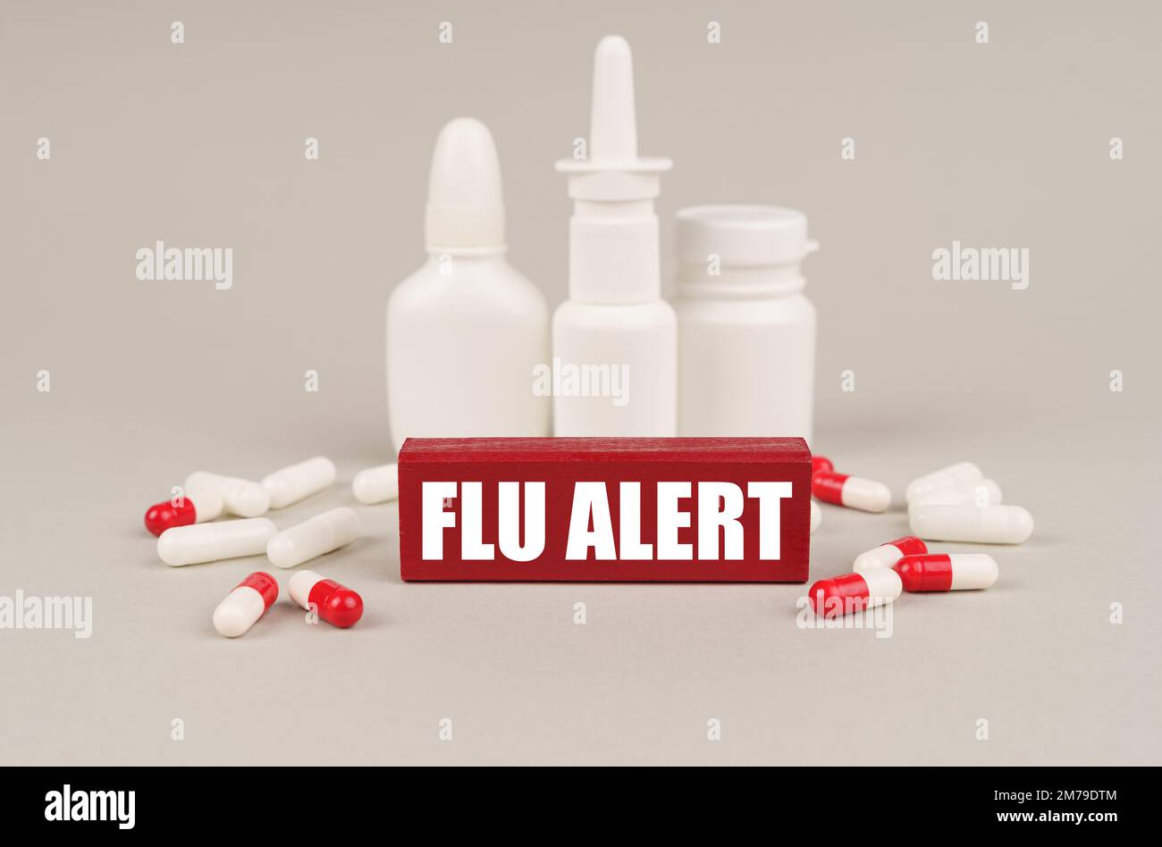 Medical concept. On a gray surface are pills, white jars and a red wooden block with the inscription - Flu alert Stock Photo