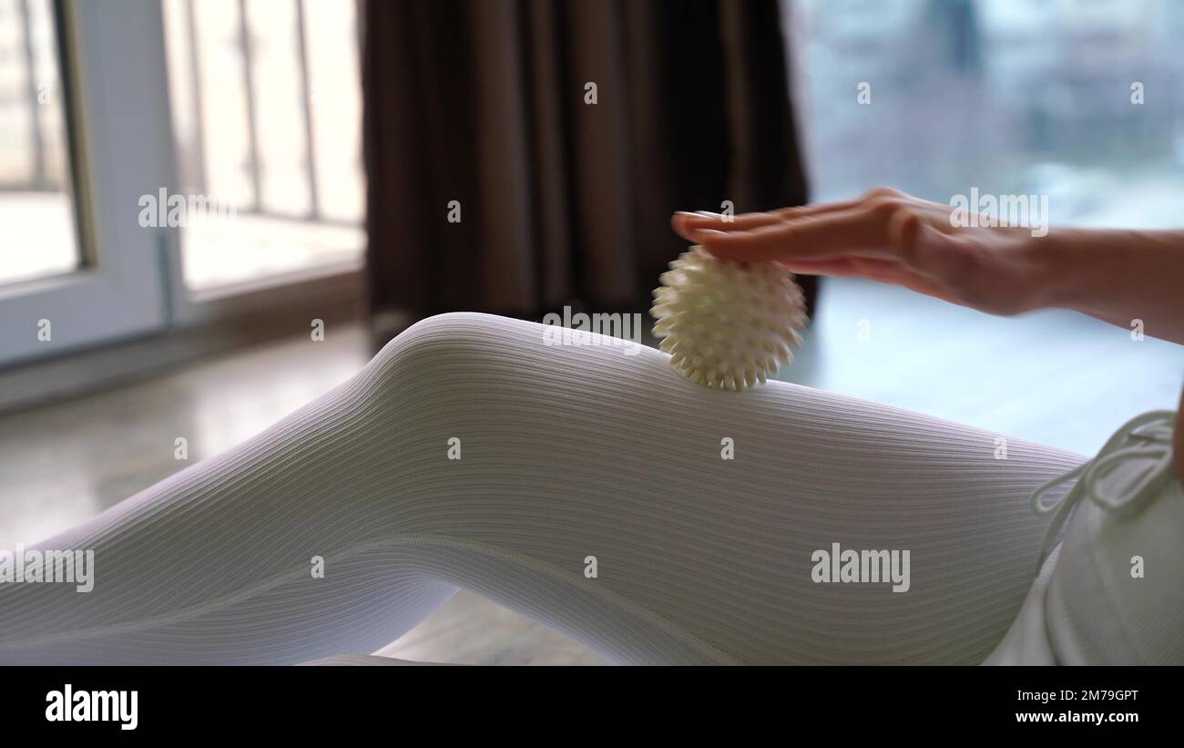 Athletic slim caucasian woman doing thigh selfmassage with a massage