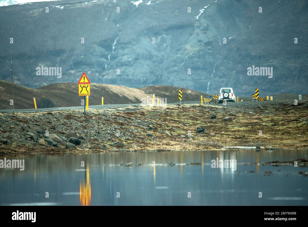 A Suzuki Jimny drives across the ring road in Iceland, with reflection and glacier in the background Stock Photo