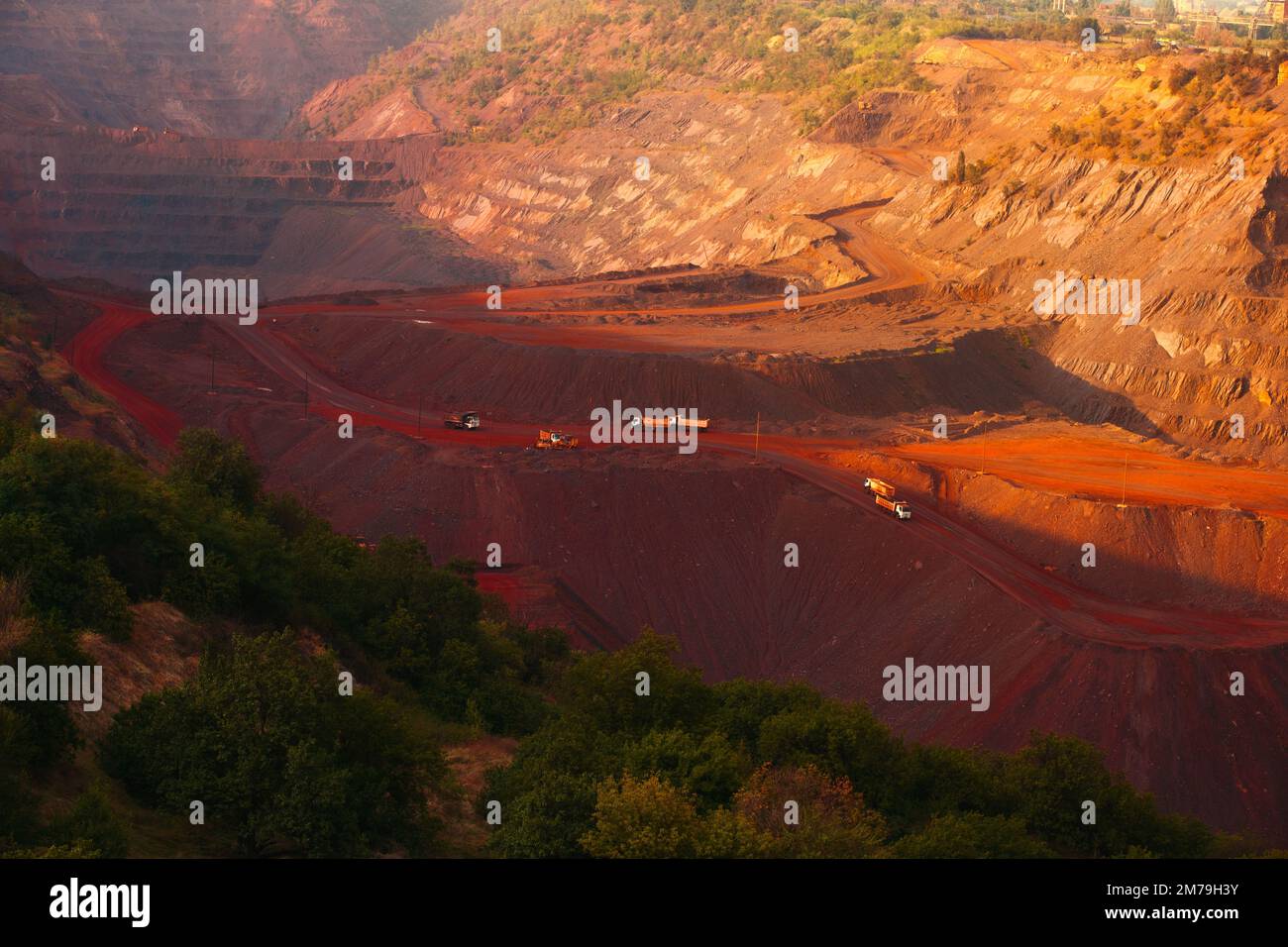 Bulldozers and trucks in quarry with red ground. Mining iron ore in Kriviy Rih, Ukraine. Industrial landscape Stock Photo