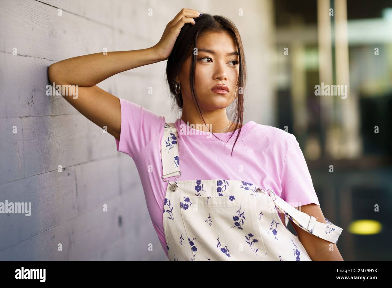Stylish Asian female leaning on wall Stock Photo