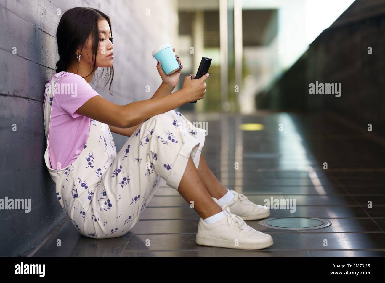 Asian female with coffee using cellphone on slope Stock Photo