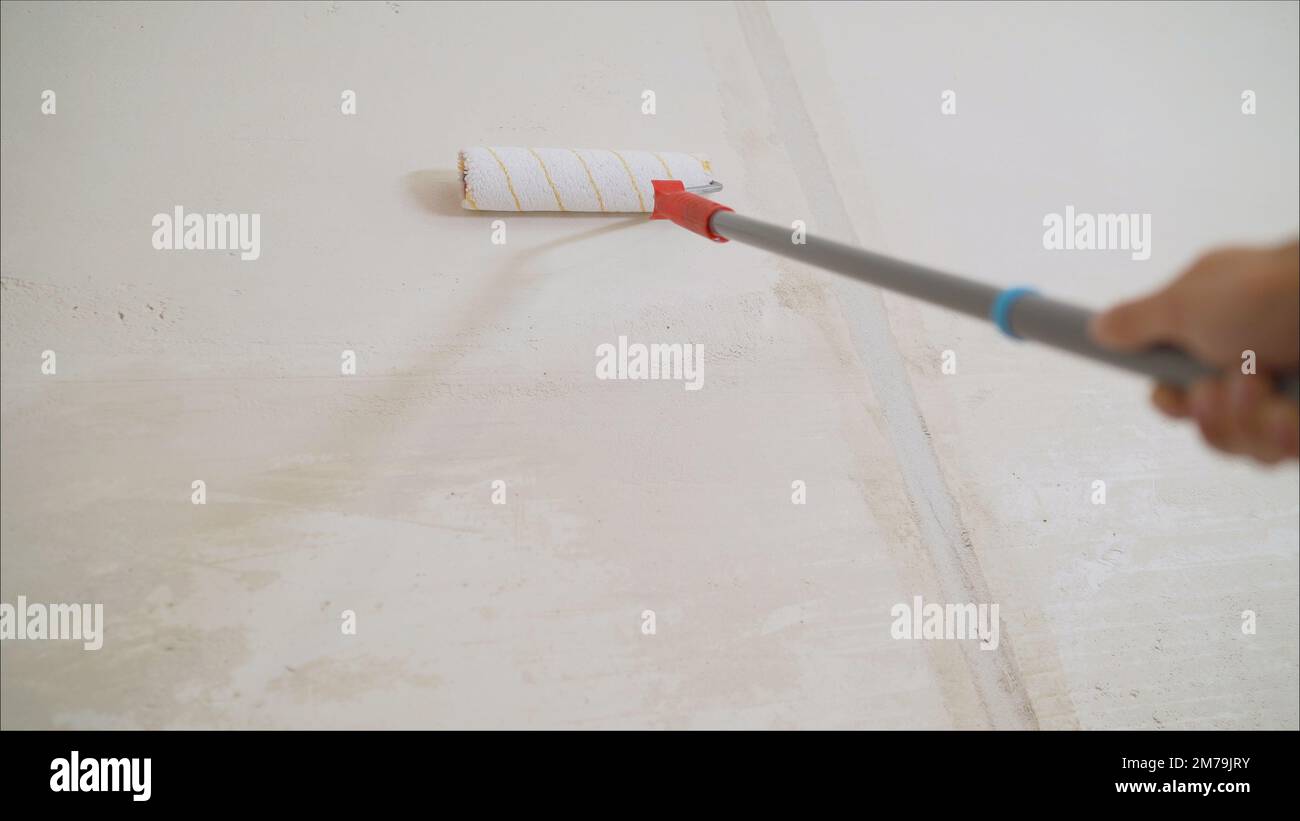 Worker priming with a paint roller. Primer worker with paint roller