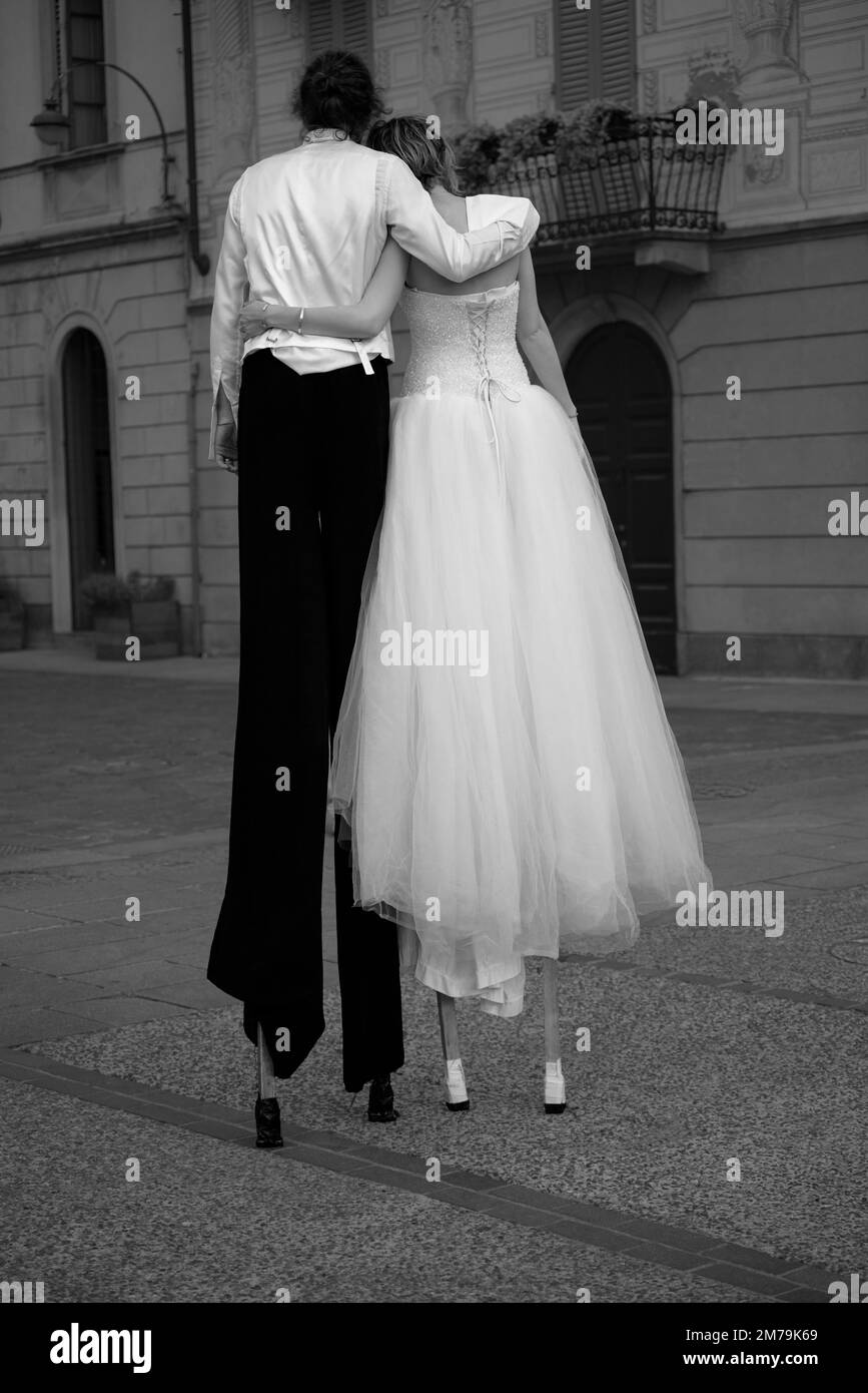 Couple dressed as a wedding walking on stilts Stock Photo